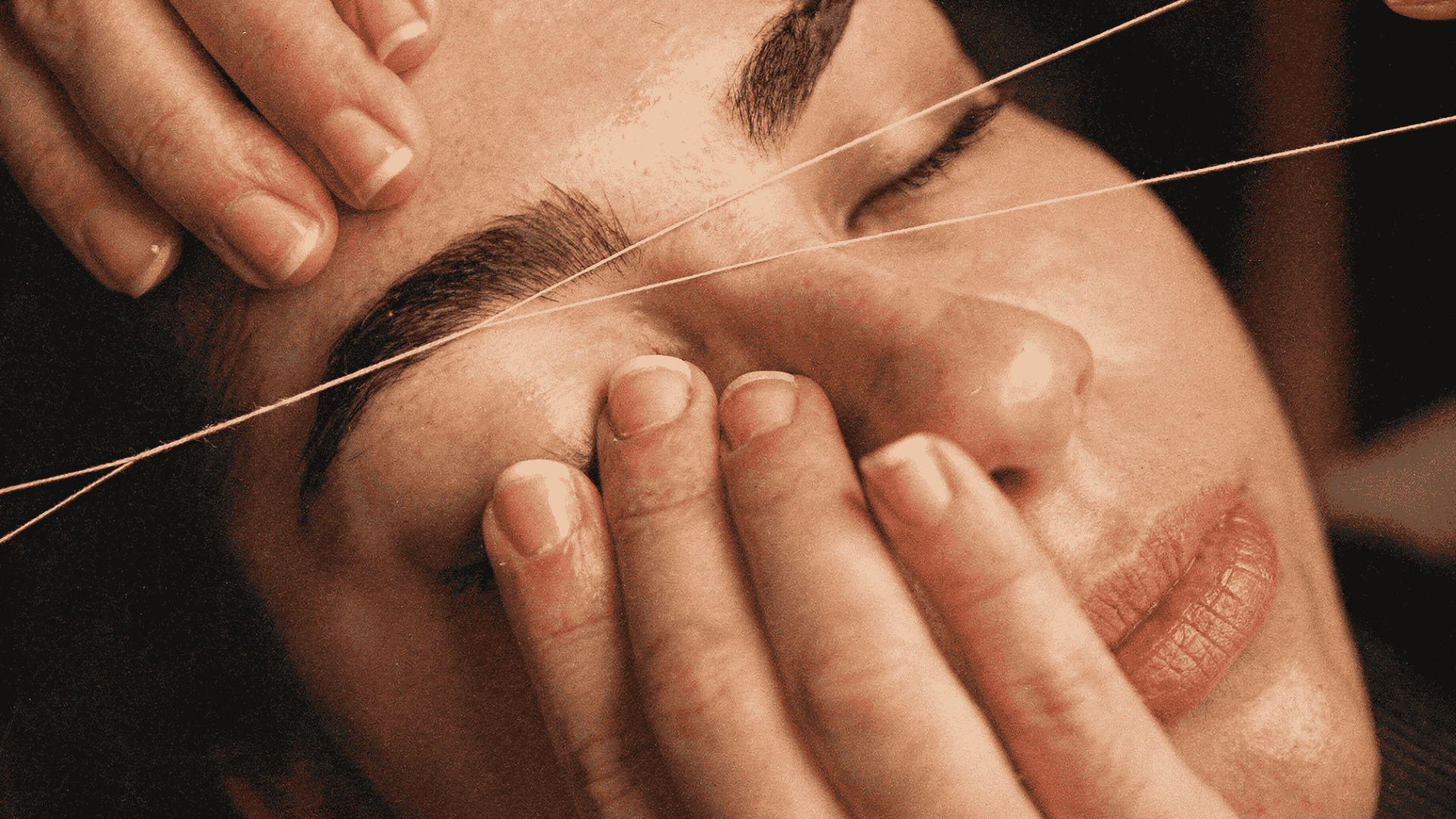 Close-up of a woman getting her eyebrows threaded at a beauty salon.