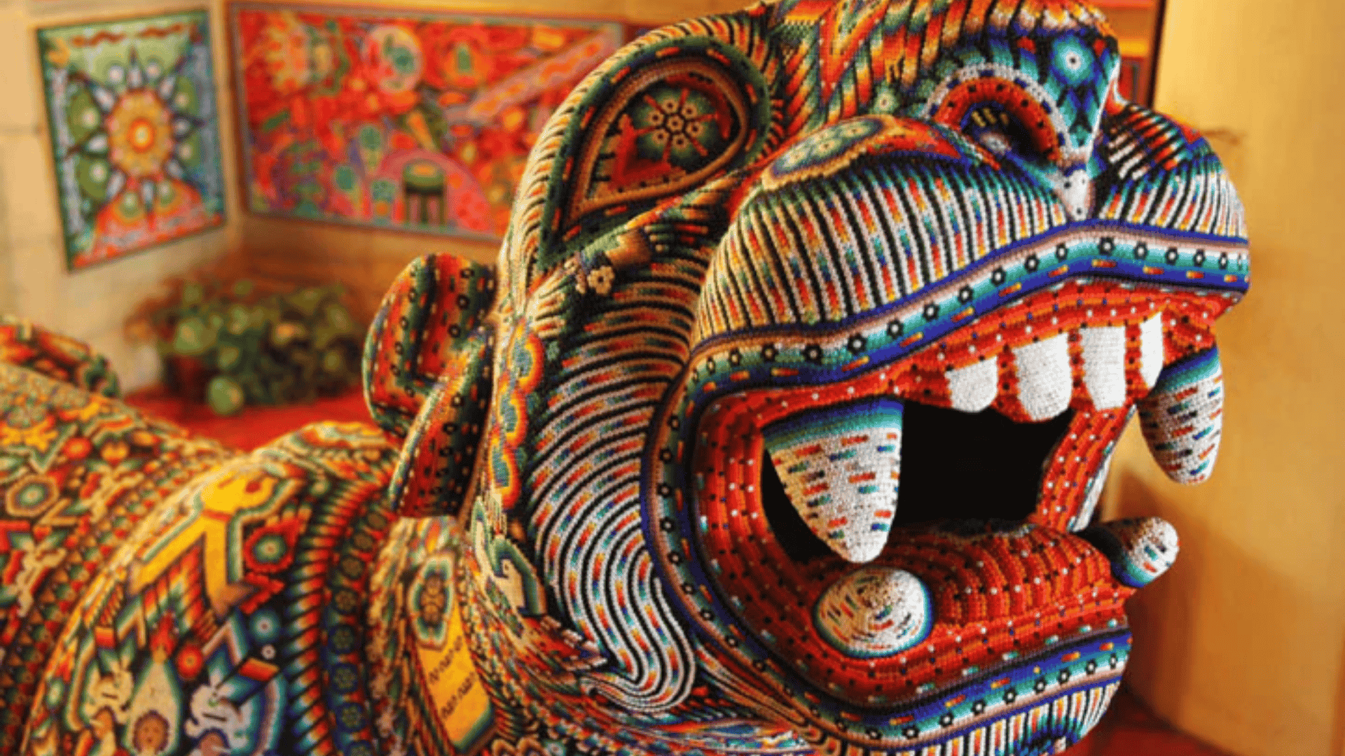 Colorful Huichol beadwork sculpture of a jaguar with intricate patterns and vibrant geometric designs covering the entire surface