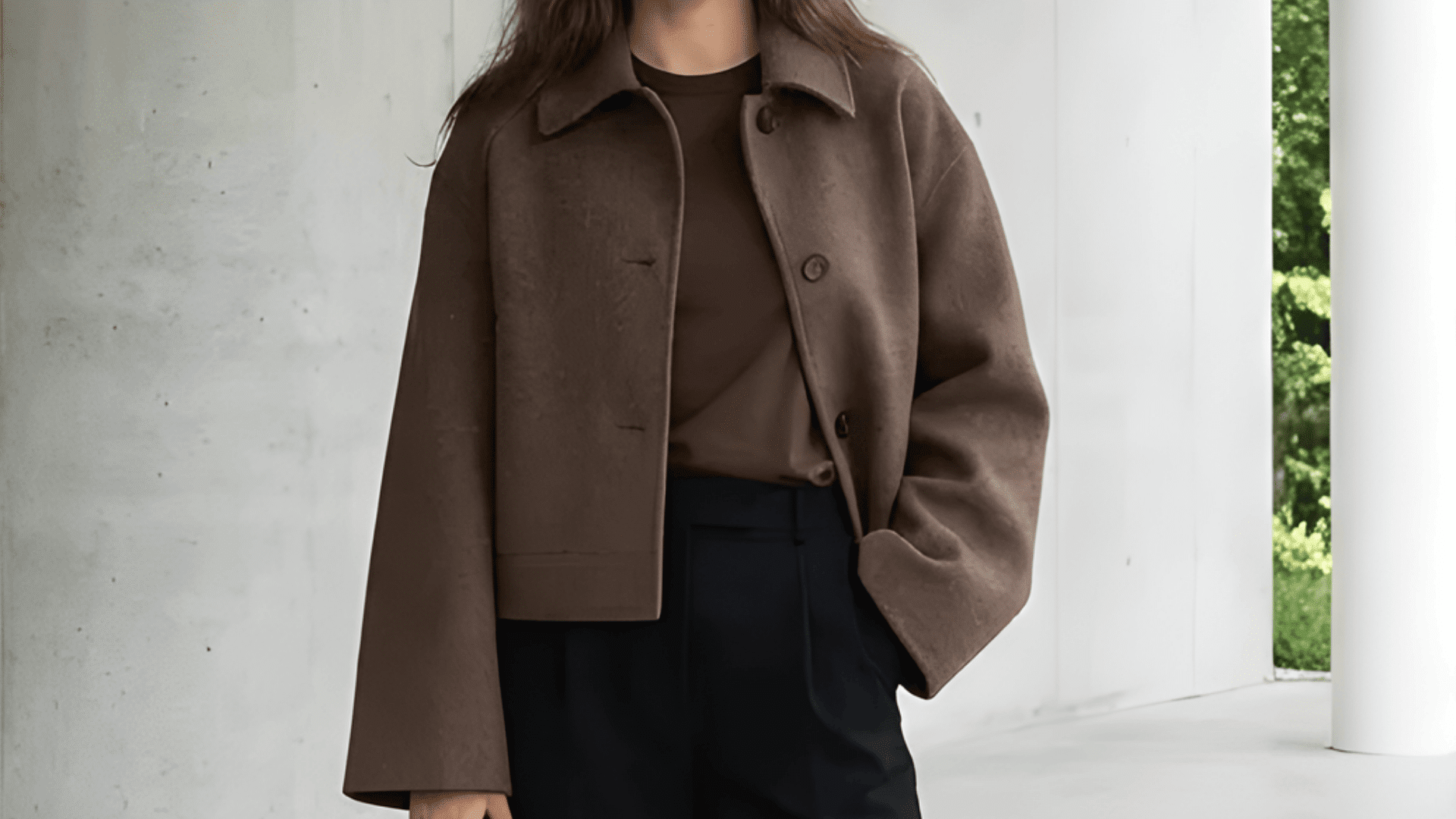 Woman in brown outfit with brown jacket in modern outdoor corridor