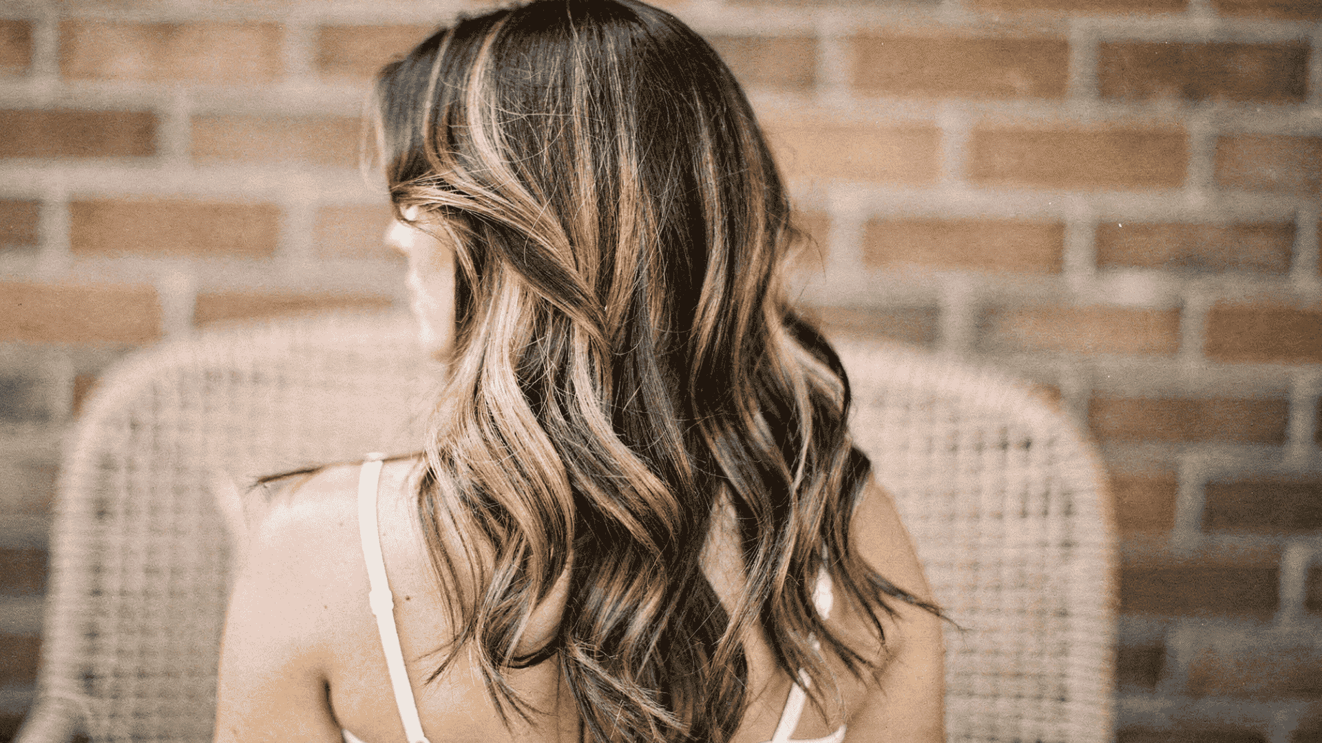 Back view of woman with blended Half-Head Highlights, showing soft contrast between natural dark hair and lighter tones for a subtle look