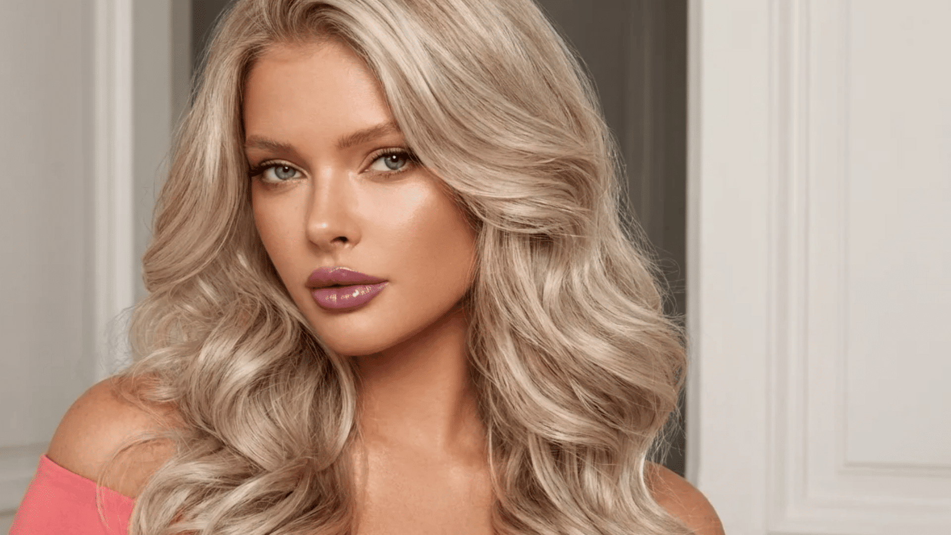 Blonde voluminous blowout with soft waves, smooth finish, and side part, creating a polished and bouncy look