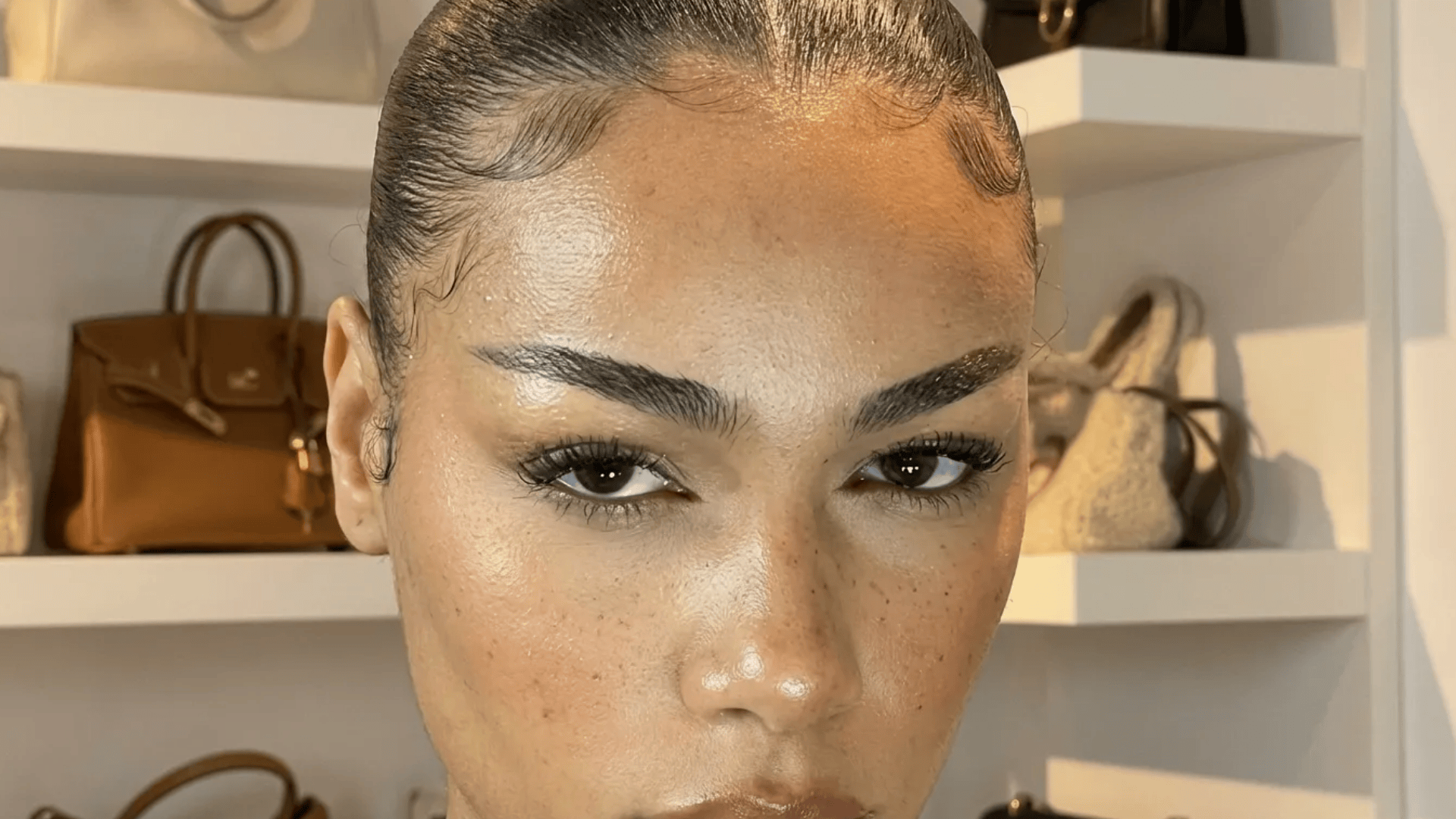 Close-up of a woman with sleek hair and defined angled eyebrows, showing a sharp arch and structured brow shape.