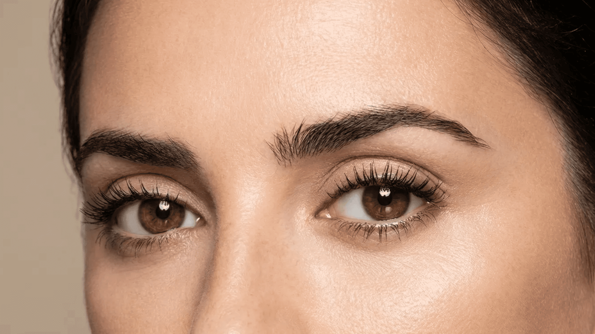 Close-up of brown eyes with natural makeup, long lashes, and full, well-defined eyebrows.