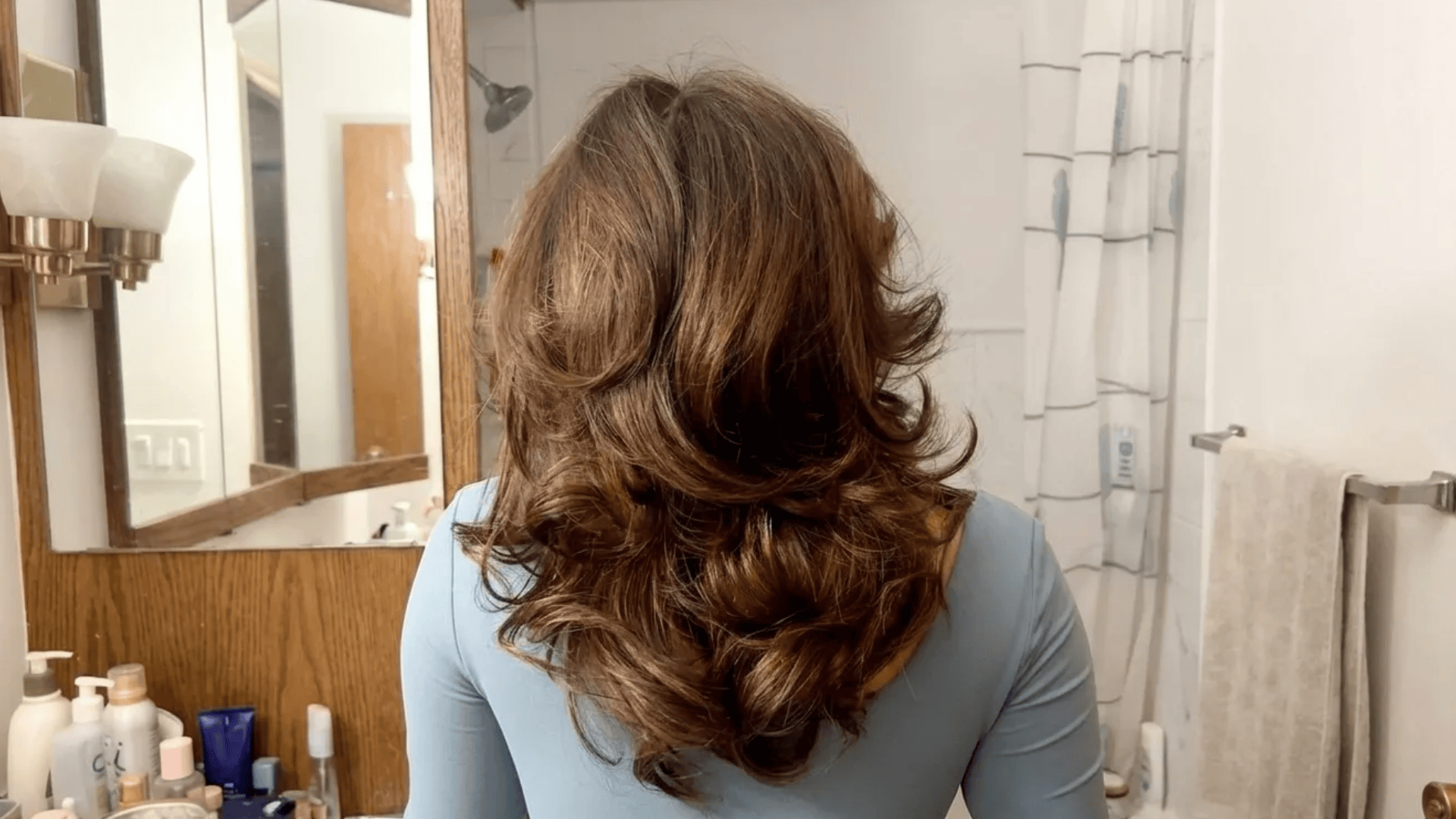 Long layered blowout with voluminous waves and soft curls, styled with lift and movement for a full, glossy finish