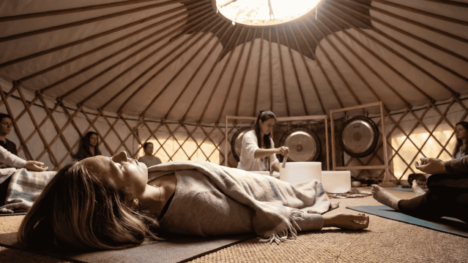 People meditating in a yurt during a sound healing session with gongs and crystal singing bowls