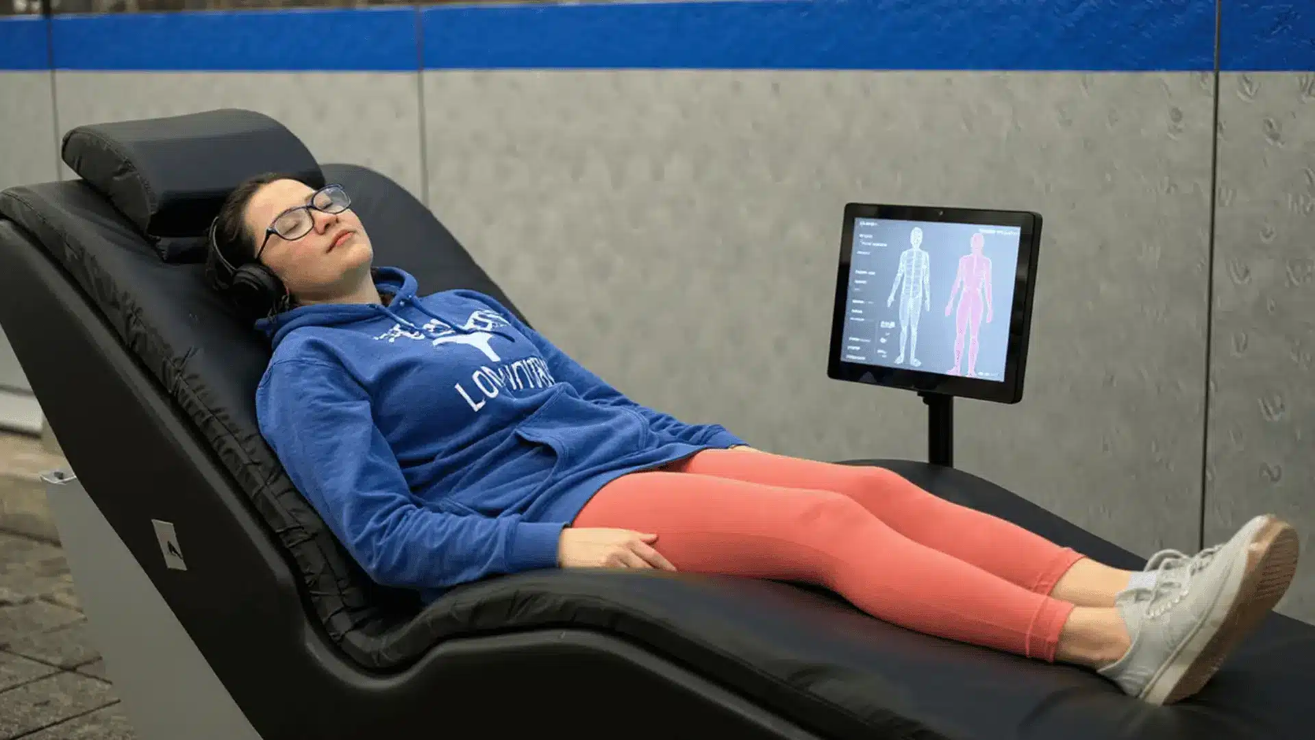 Person relaxing on a hydromassage bed with a screen displaying body areas being targeted for therapy.