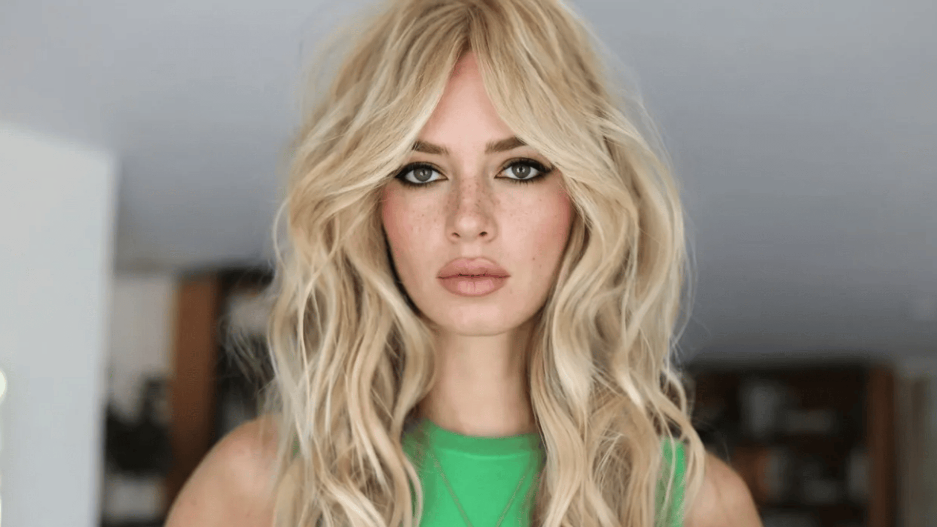 Tousled blonde blowout with soft waves, curtain-style volume, and a slightly undone texture for a relaxed, airy finish