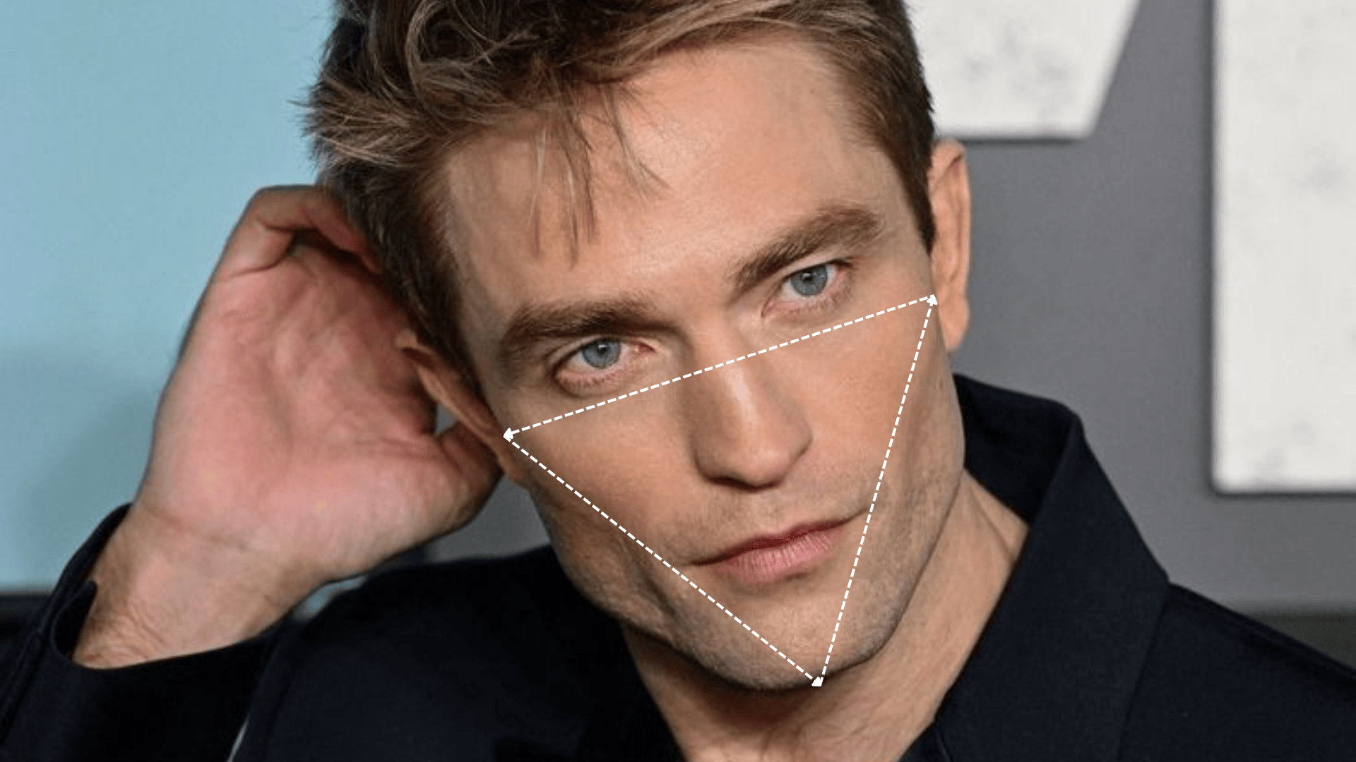 Close-up of a person Robert Pattinson with a defined jawline, with a dashed triangle overlay highlighting facial proportions and structure.