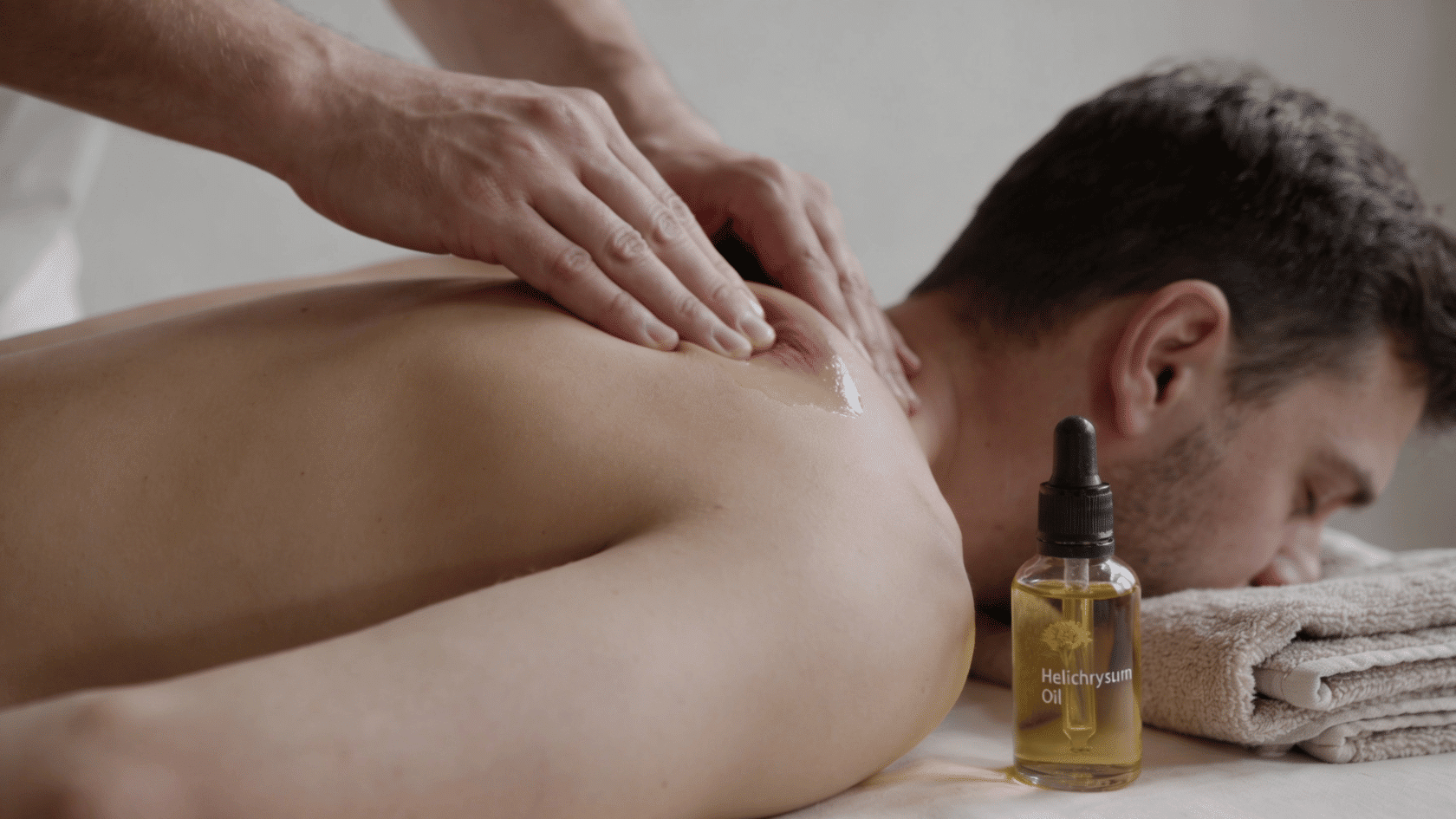Helichrysum oil bottle and towel arranged for muscle massage use