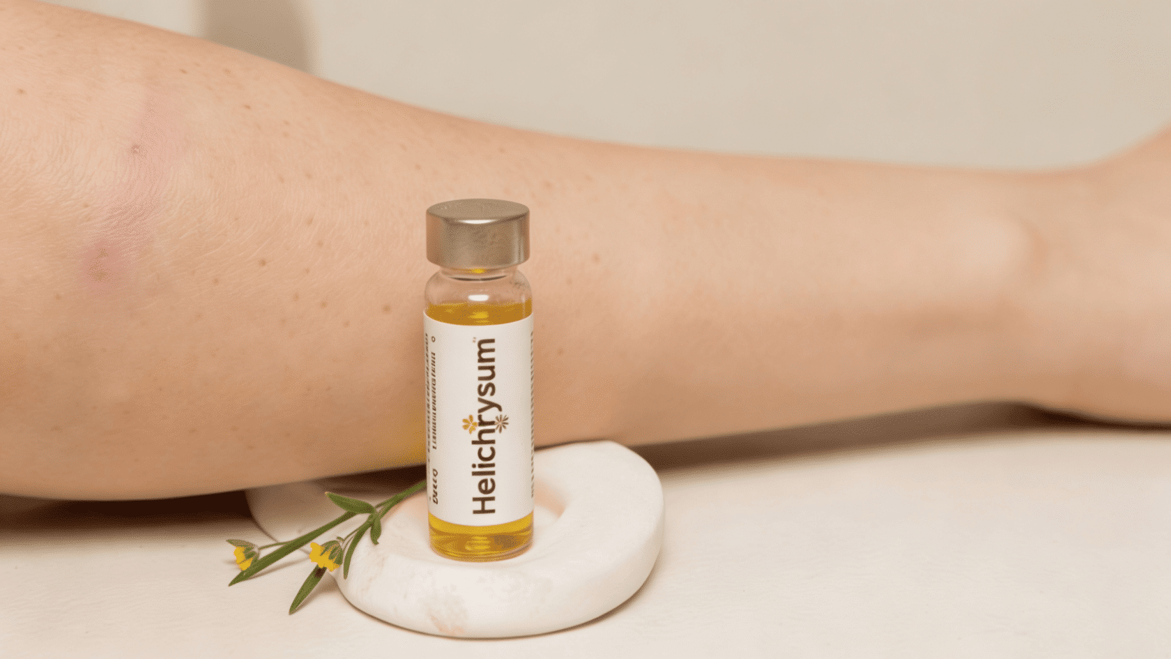Helichrysum oil bottle placed near a bruised hand with yellow flowers, showing natural skincare and healing support