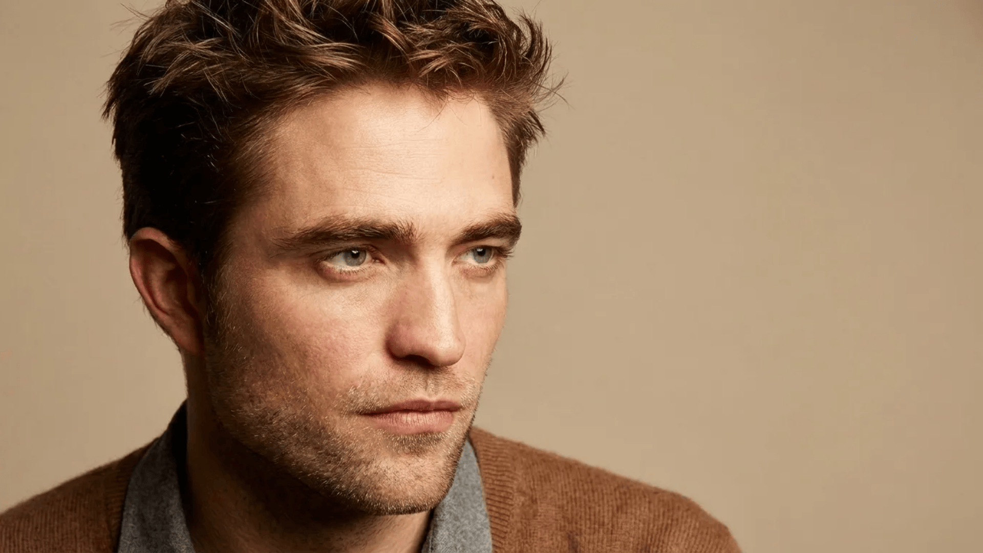 Man with short textured haircut and light stubble, styled with natural volume and a slightly messy finish