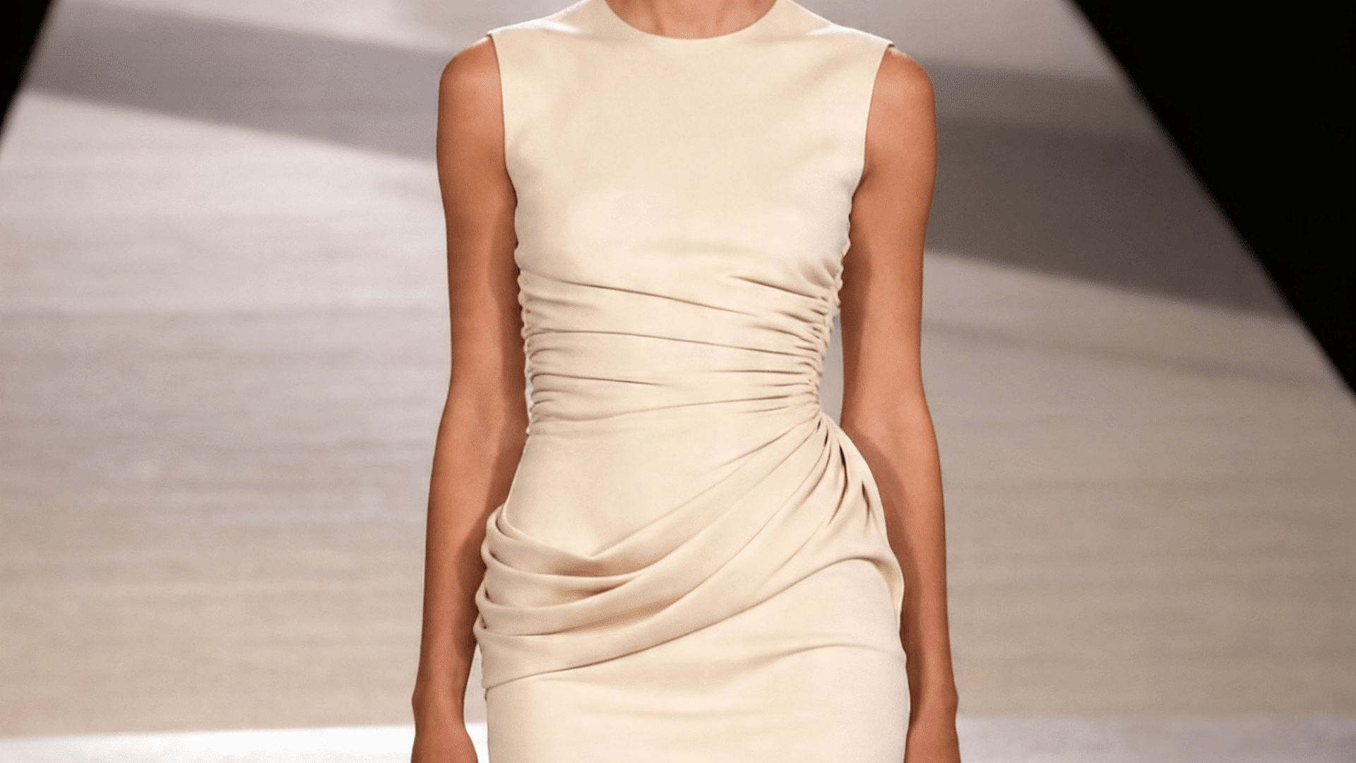 sleeveless beige dress with ruched fabric across the waist and hips on a runway model