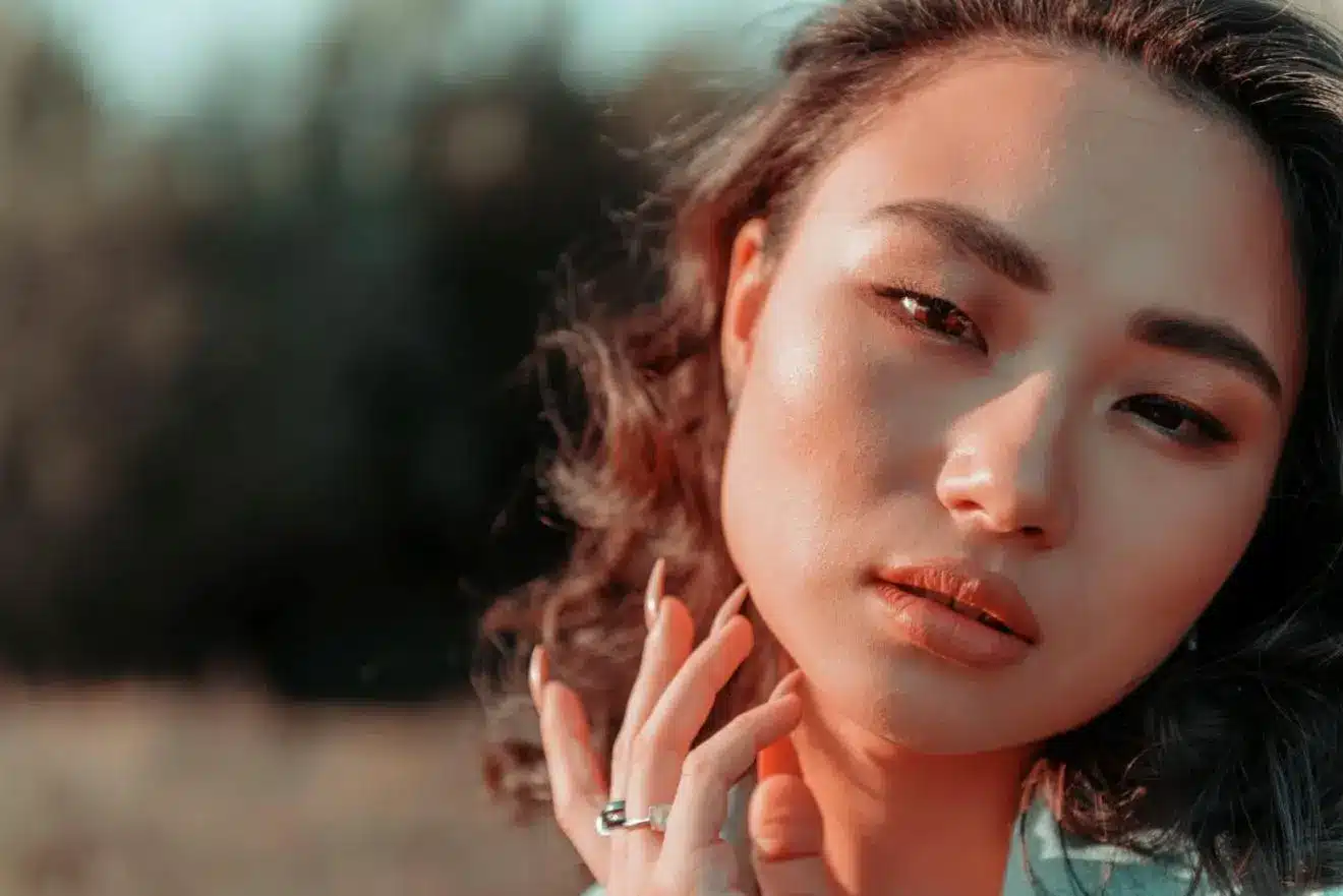 Close-up of a person with wavy hair in soft natural light outdoors