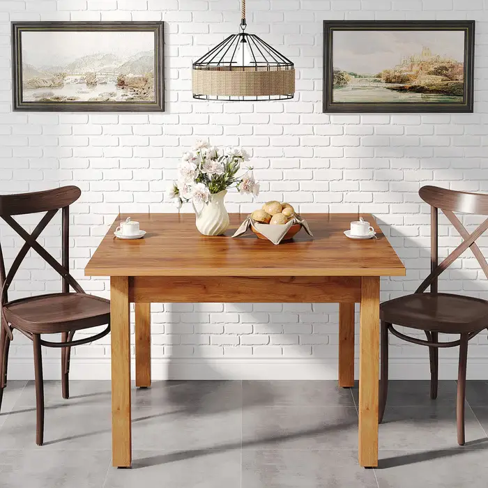 Wooden dining table with vase of flowers and bread basket in bright room with white brick wall
