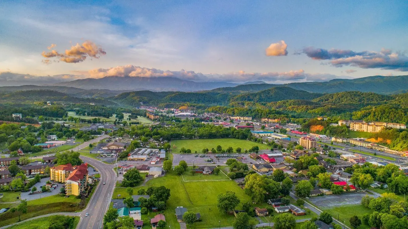 Aerial view of a town surrounded by lush green hills under a vibrant sky