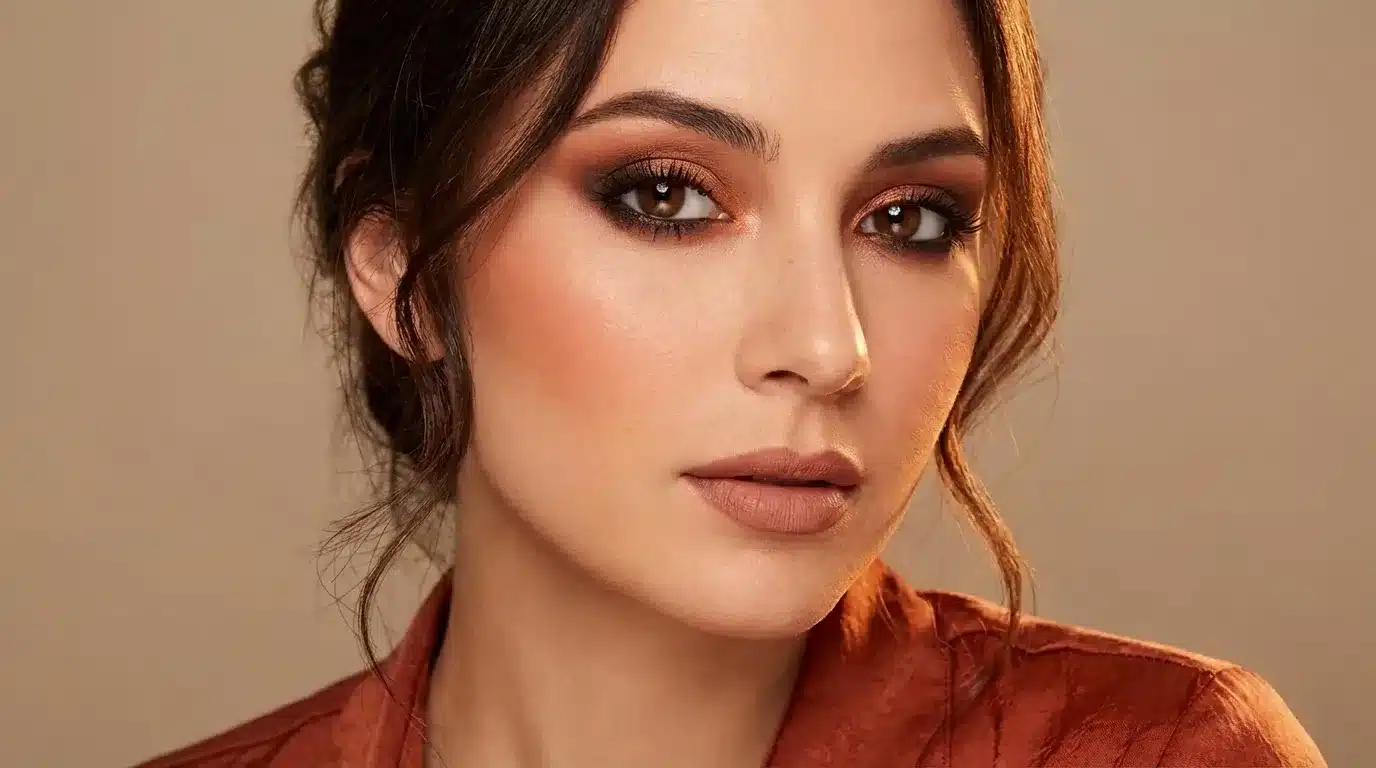 A woman with deep autumn coloring wearing a warm smokey eye look with bronze and burnt sienna eyeshadow, soft blush, and a nude lip.