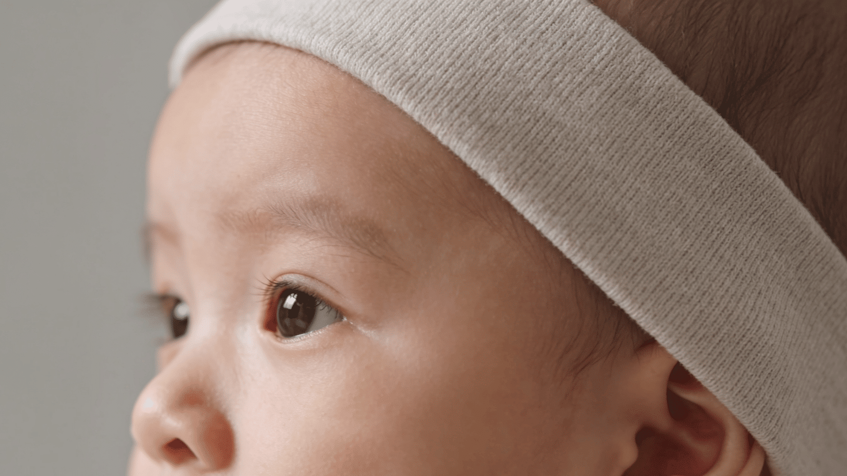 Baby wearing a simple headband in a close-up indoor portrait with neutral background