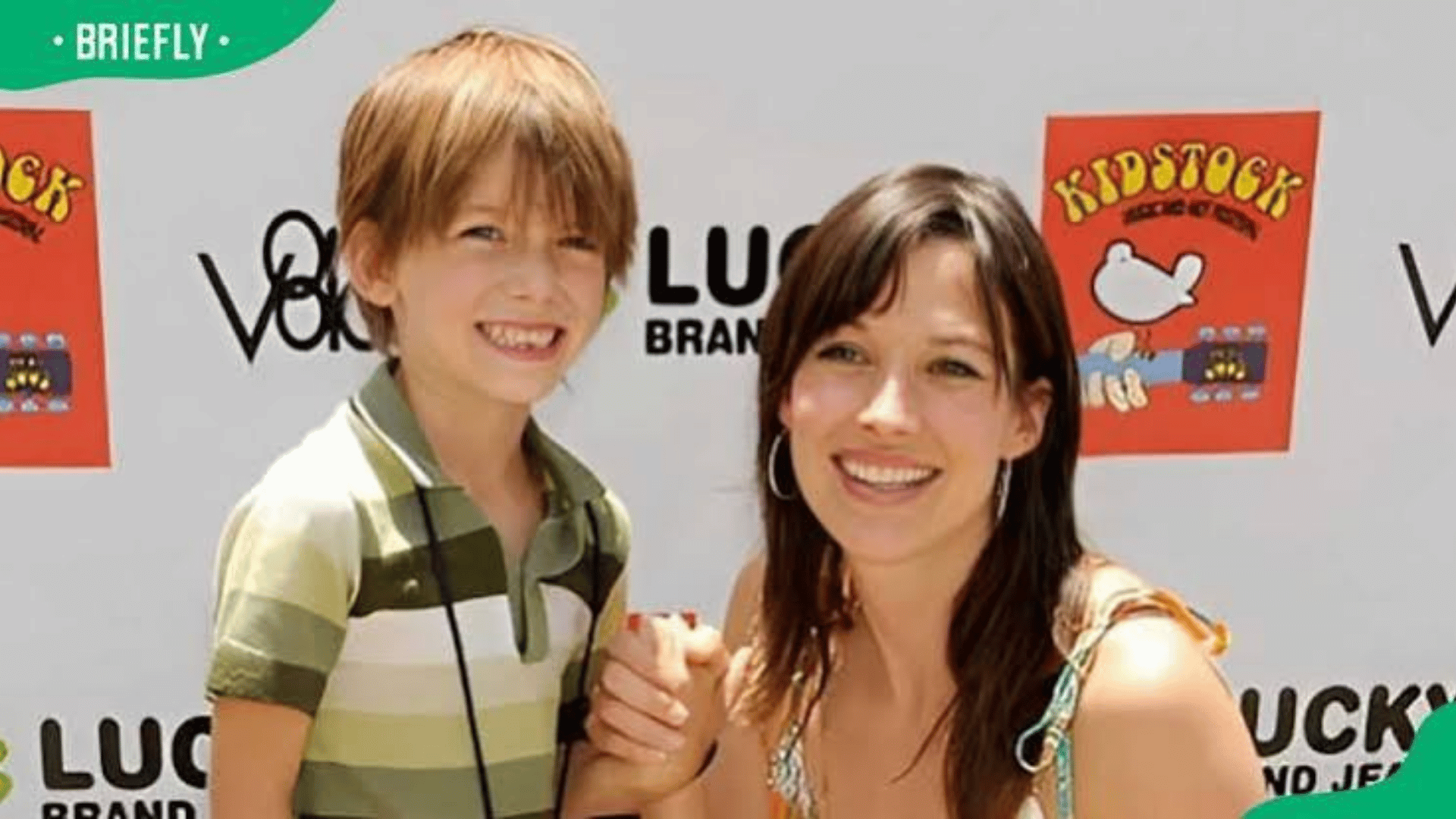 Brooke Langton smiling and holding hands with her young son at the Kidstock charity event