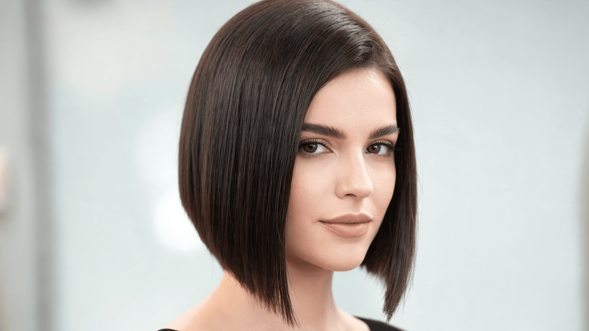 Woman with an asymmetrical sew-in bob featuring shorter and longer angled sides.