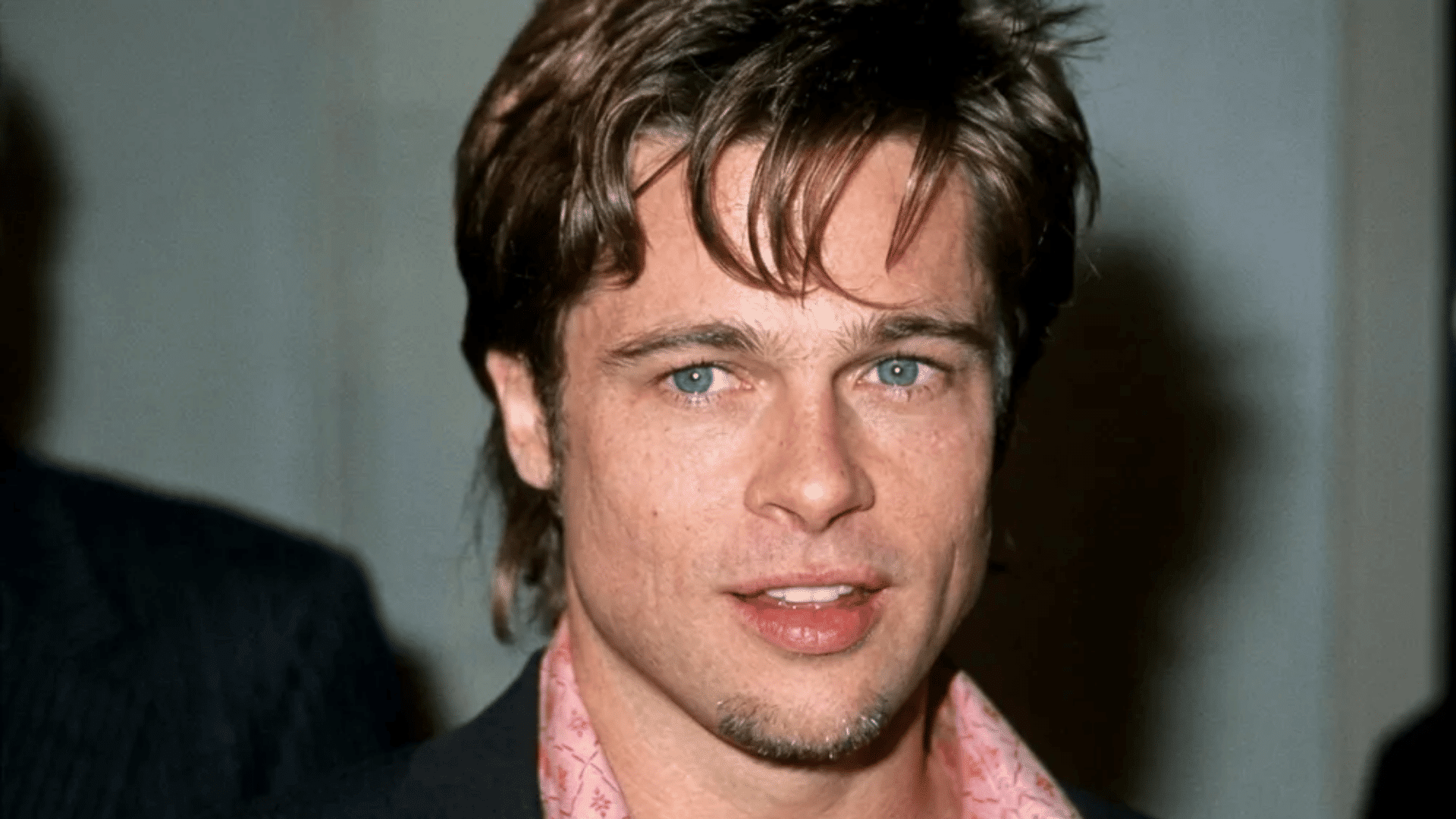 Brad Pitt with short mullet haircut featuring layered brown hair, light textured top, and subtle longer back, facing forward in an indoor setting.