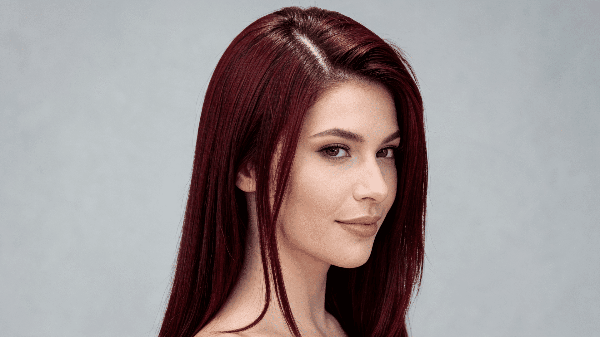 Woman with a burgundy side-part sew-in hairstyle featuring a deep red tone and swept-over shape.