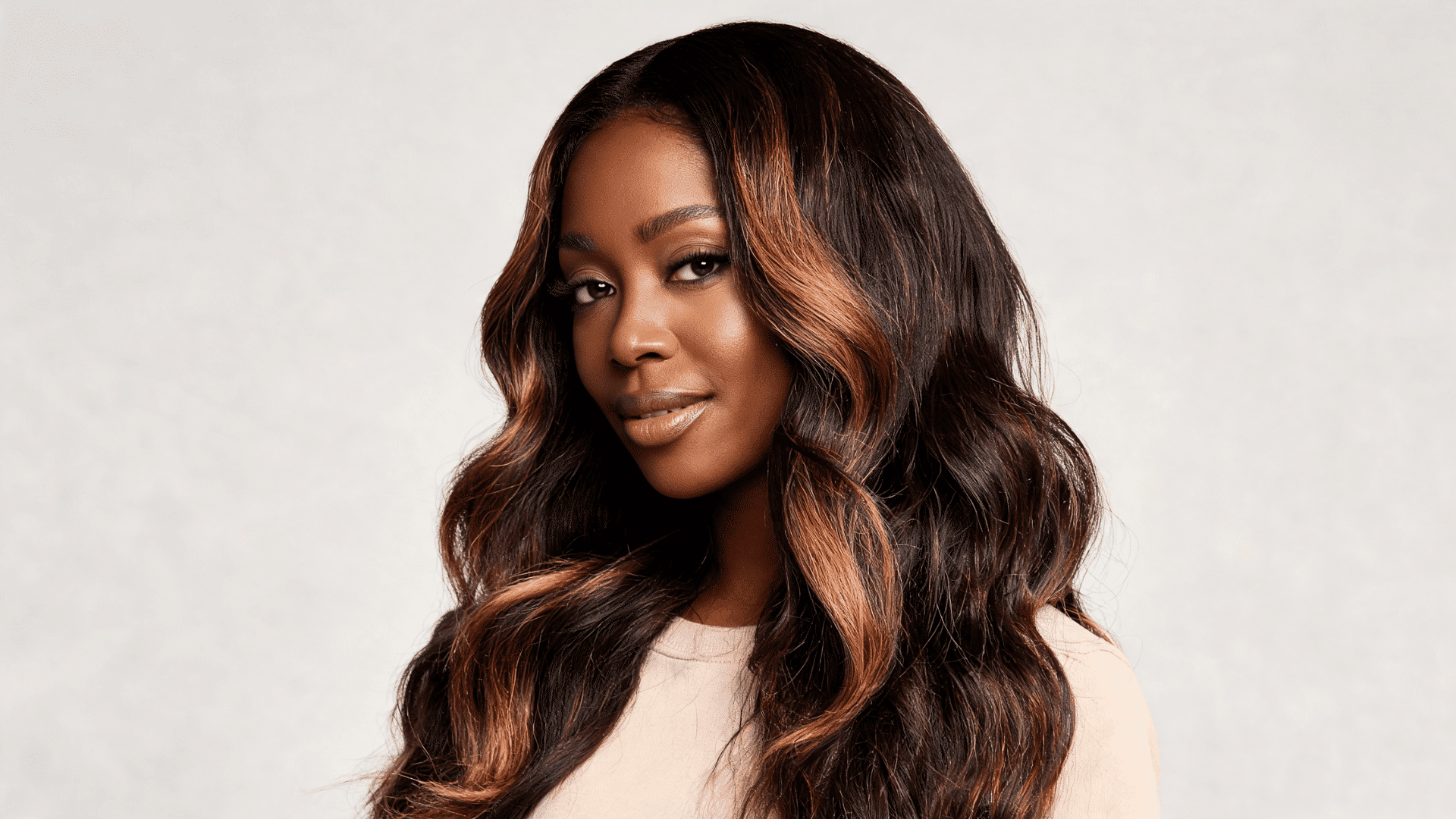Woman wearing caramel highlight body waves with warm tones and loose texture