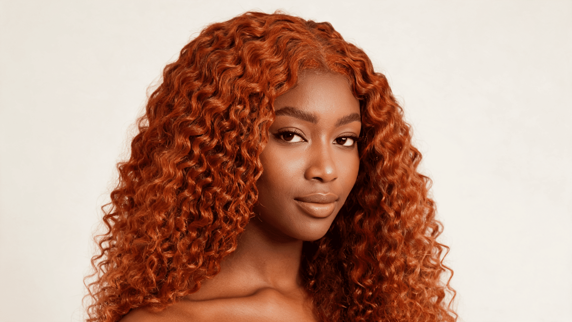 Woman wearing a copper curly sew-in with defined curls and warm red tones