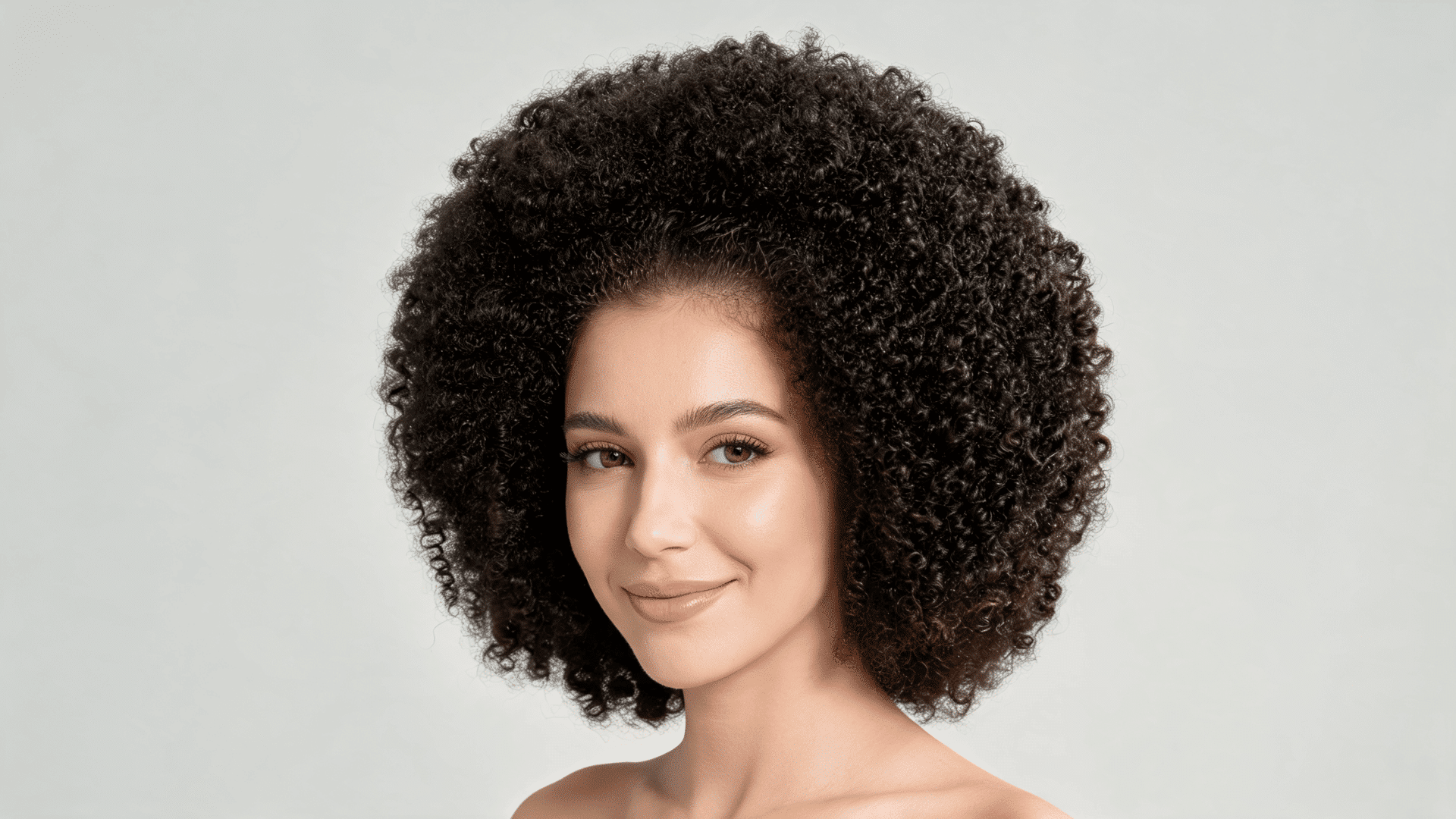 Woman with a natural Afro curly sew-in hairstyle featuring rounded volume and coily curls.