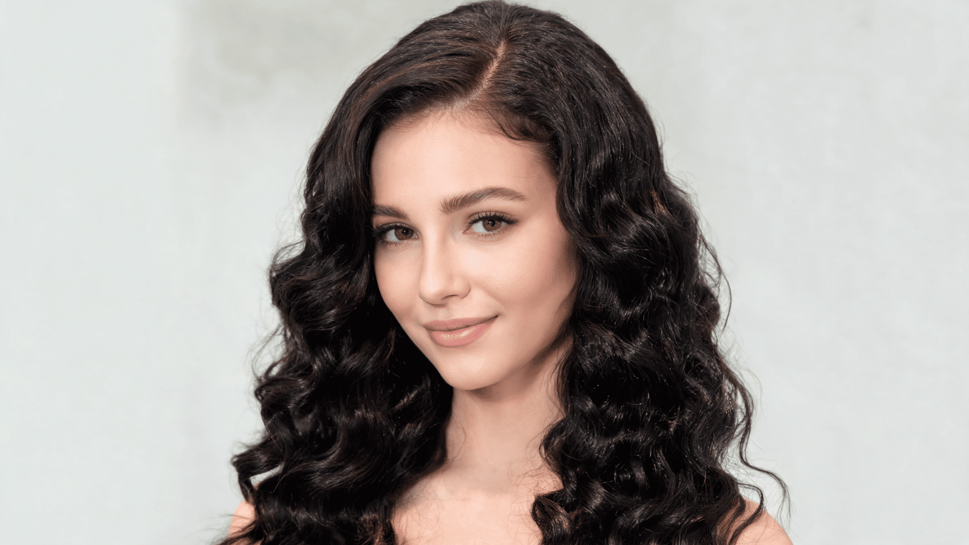 Woman with a deep wave side-part sew-in hairstyle featuring defined waves and added volume.