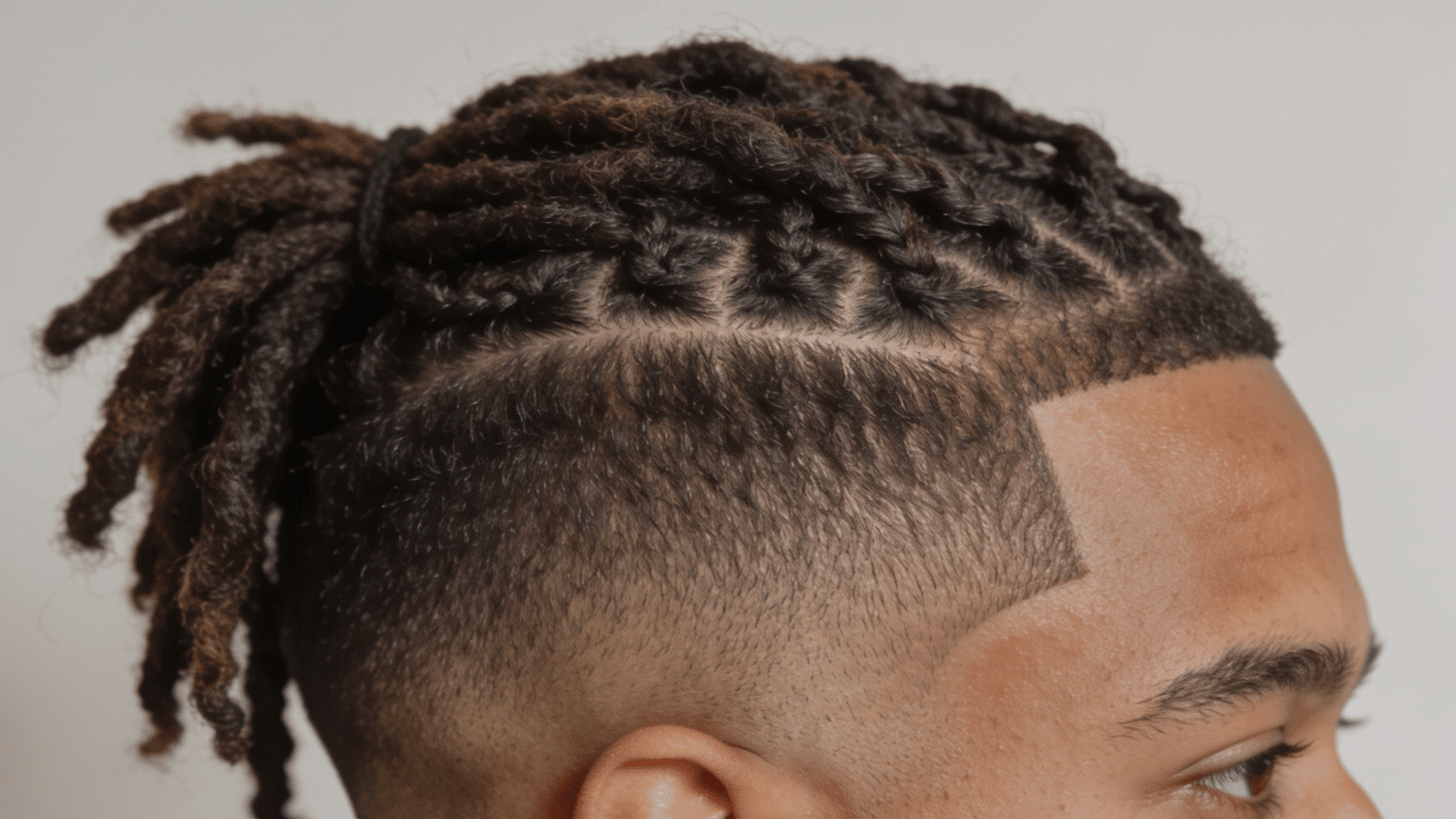 Mid fade with locs styled on top and clean tapered sides at the temple area