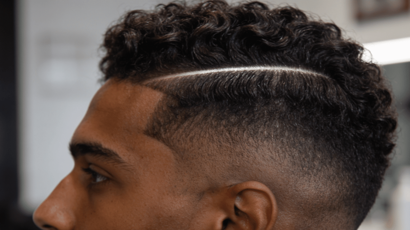 Close-up of mid fade with 360 wave pattern and hard part line on short hair