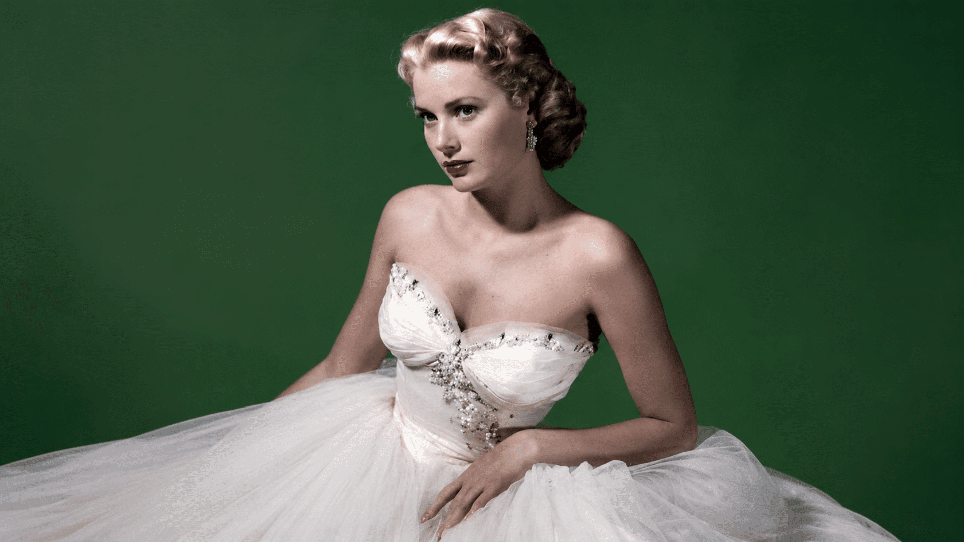 Vintage Hollywood portrait of a woman in a white strapless gown against a green background, showing classic 1950s glamour.