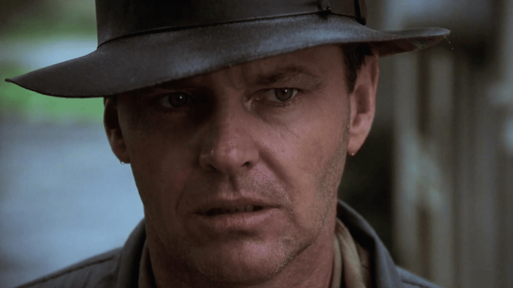 Close-up of a man wearing a fedora hat with an intense expression cinematic film still look and moody lighting