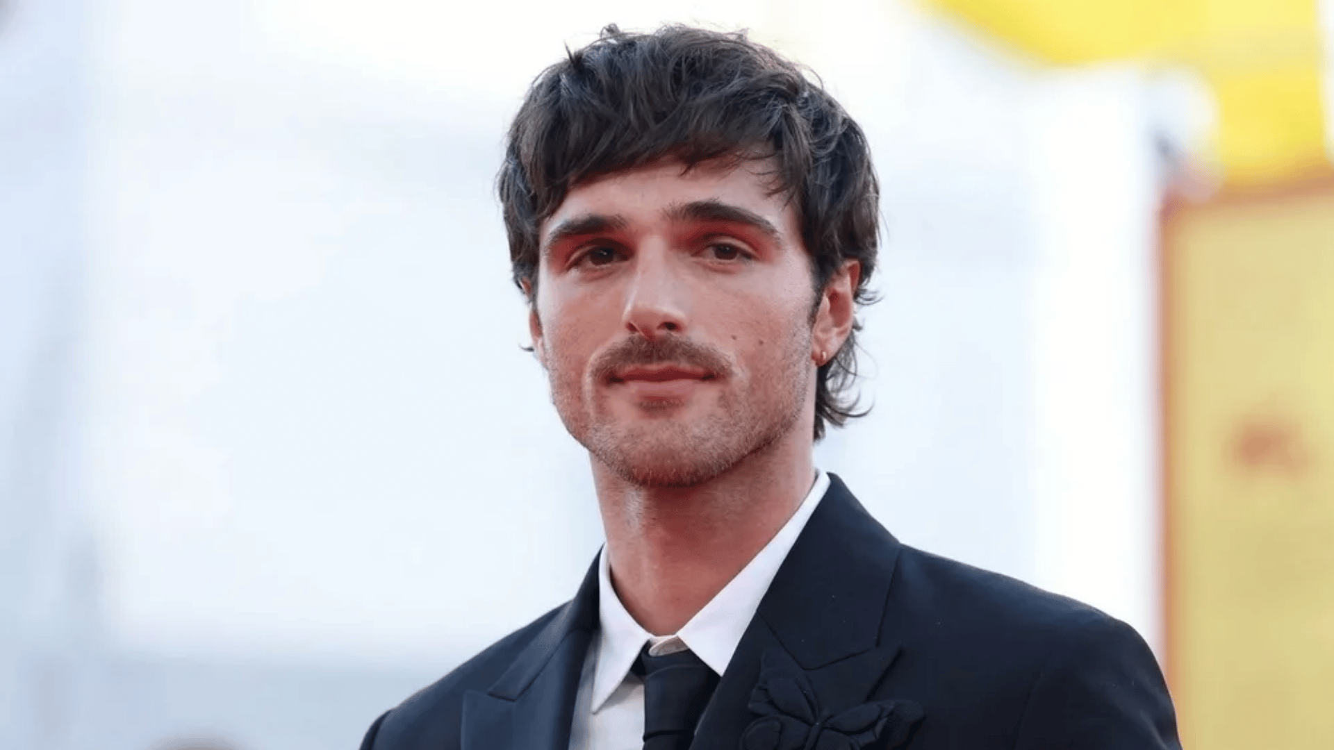 Jacob Elordi wearing suit, short mullet haircut with textured layers and subtle longer back at event.