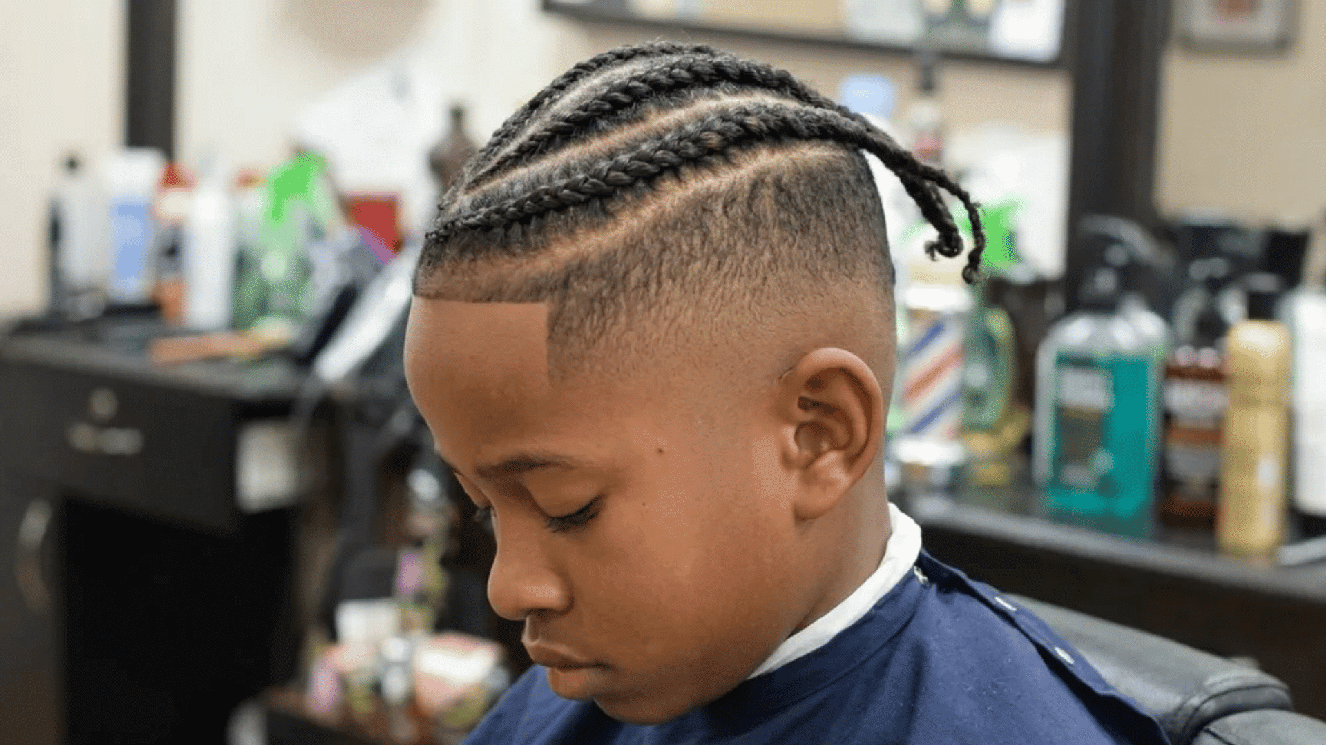 Mixed boys haircuts braided top with high fade on a young boy in barber shop, cornrow style with clean sides and sharp lineup