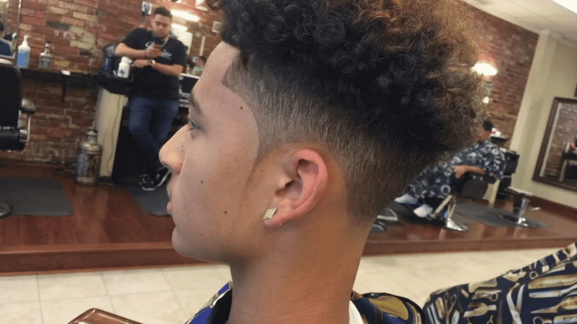Mixed boys haircuts curly top with mid fade fade haircut on side profile in barber shop