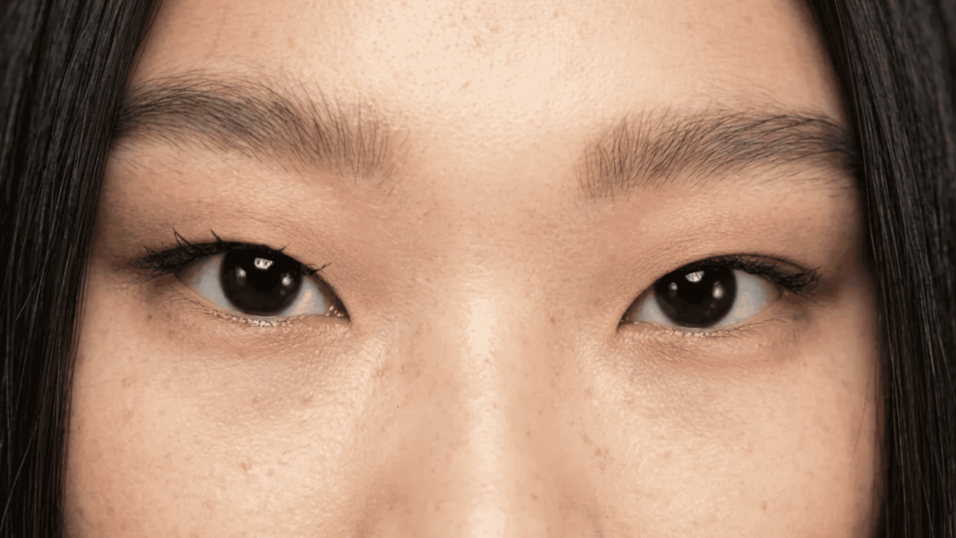 Close-up of eyes, monolid eyelids, natural makeup, dark straight hair framing the face