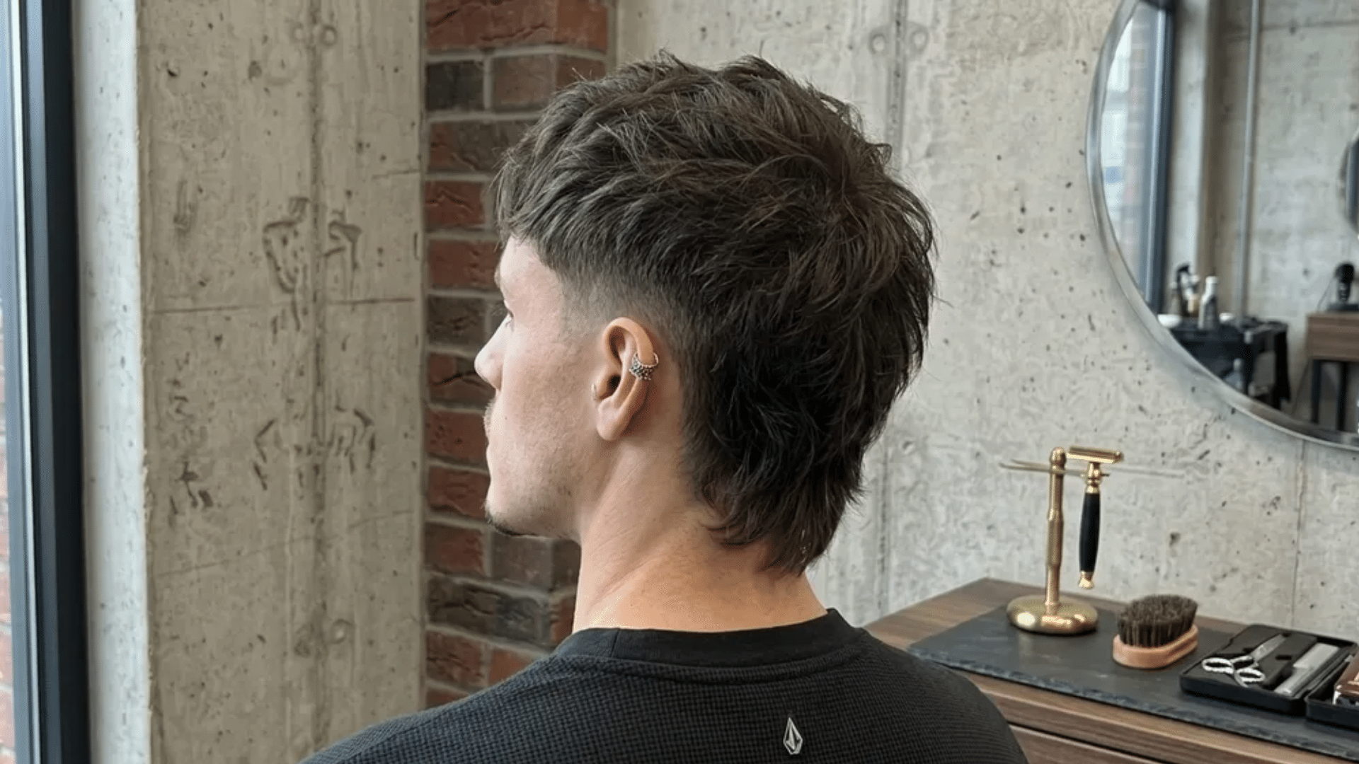 Short mullet haircut back view in barbershop showing textured layers, tapered sides, and slightly longer back section.