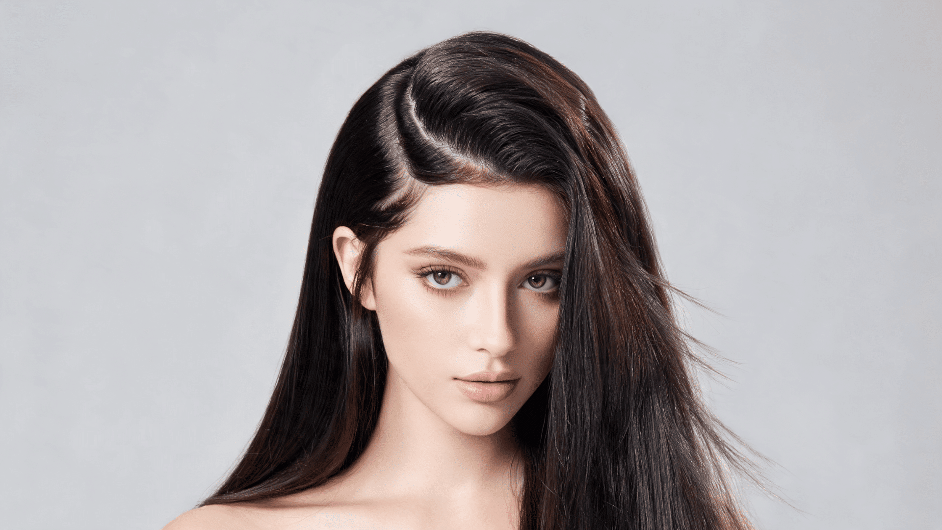 Close-up portrait showing a sleek side-part hairstyle with smooth, straight dark hair.
