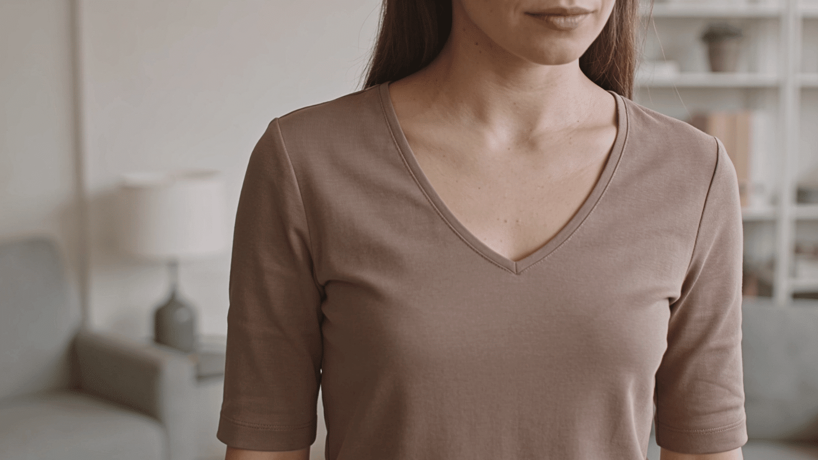 Woman wearing a V-neck top with three-quarter sleeves in a simple indoor setting
