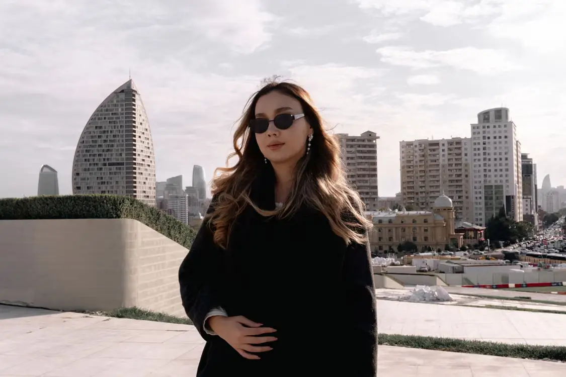 Woman in sunglasses standing outdoors with city skyscrapers in the background
