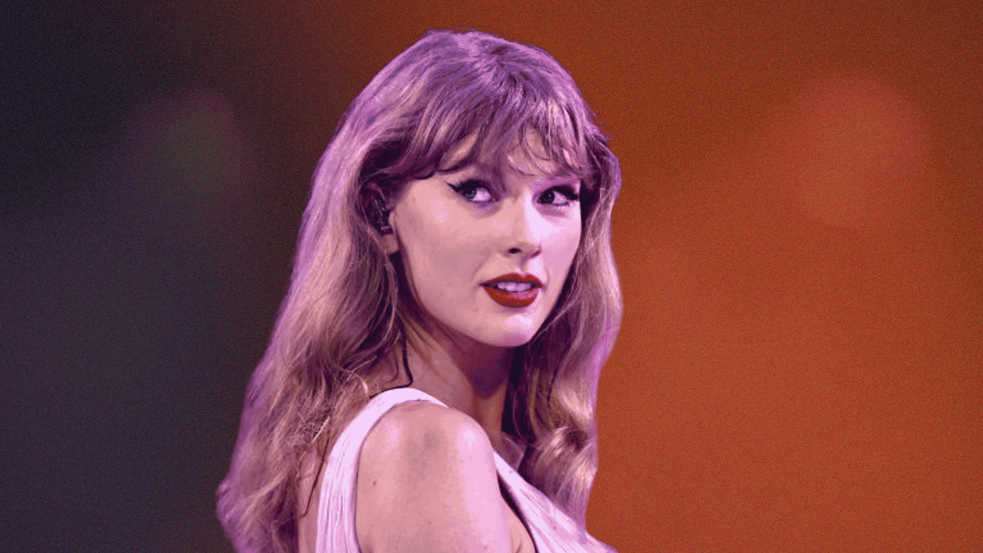 Taylor Swift singing into a microphone on stage in a sparkly blue outfit