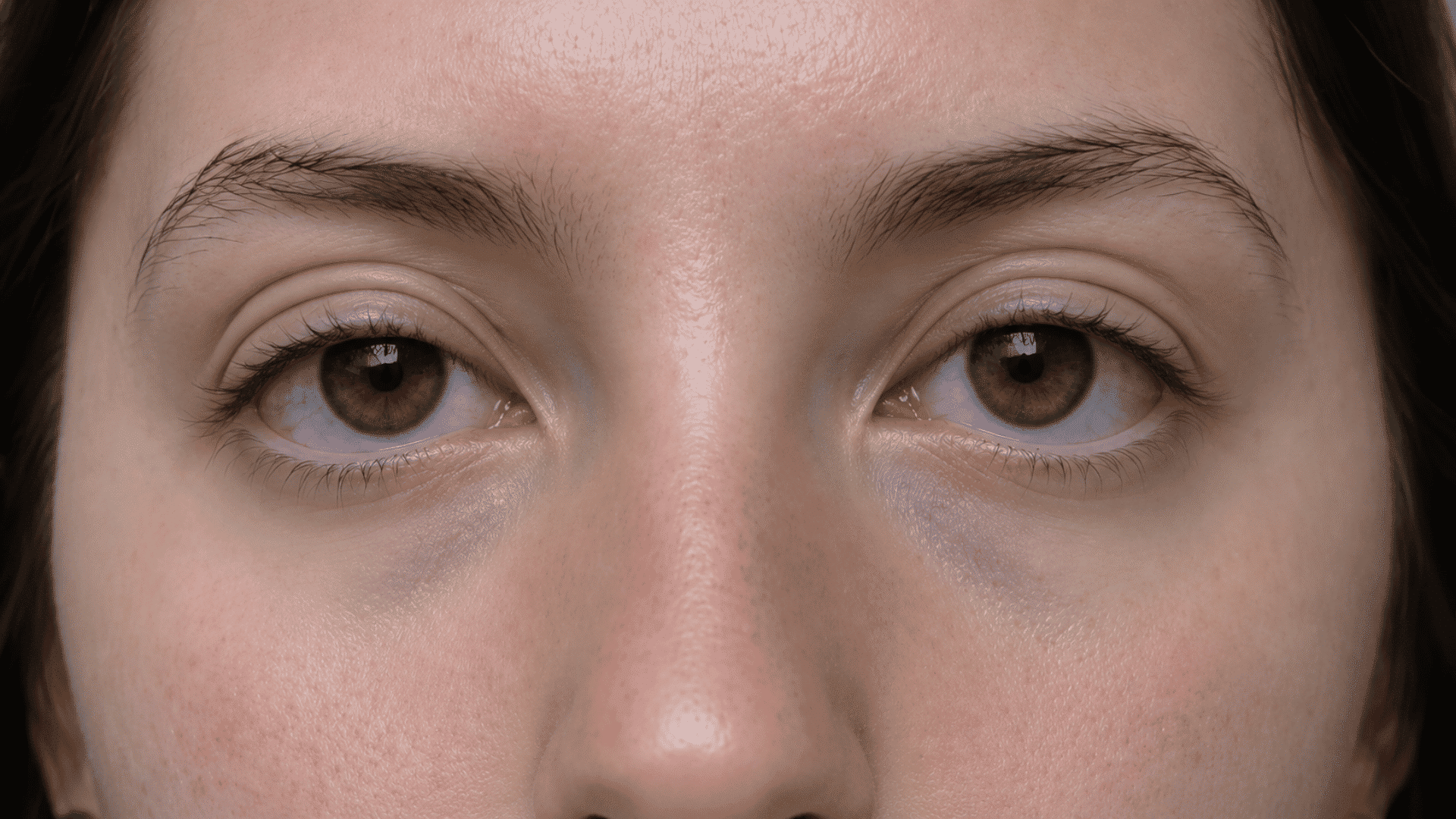 Close-up of hazel eyes with multiple visible eyelid creases, eyebrows, and natural skin texture visible
