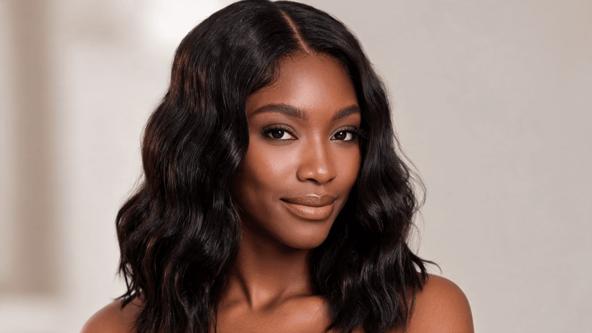 Woman wearing a shoulder-length wavy sew-in with loose waves and a middle part