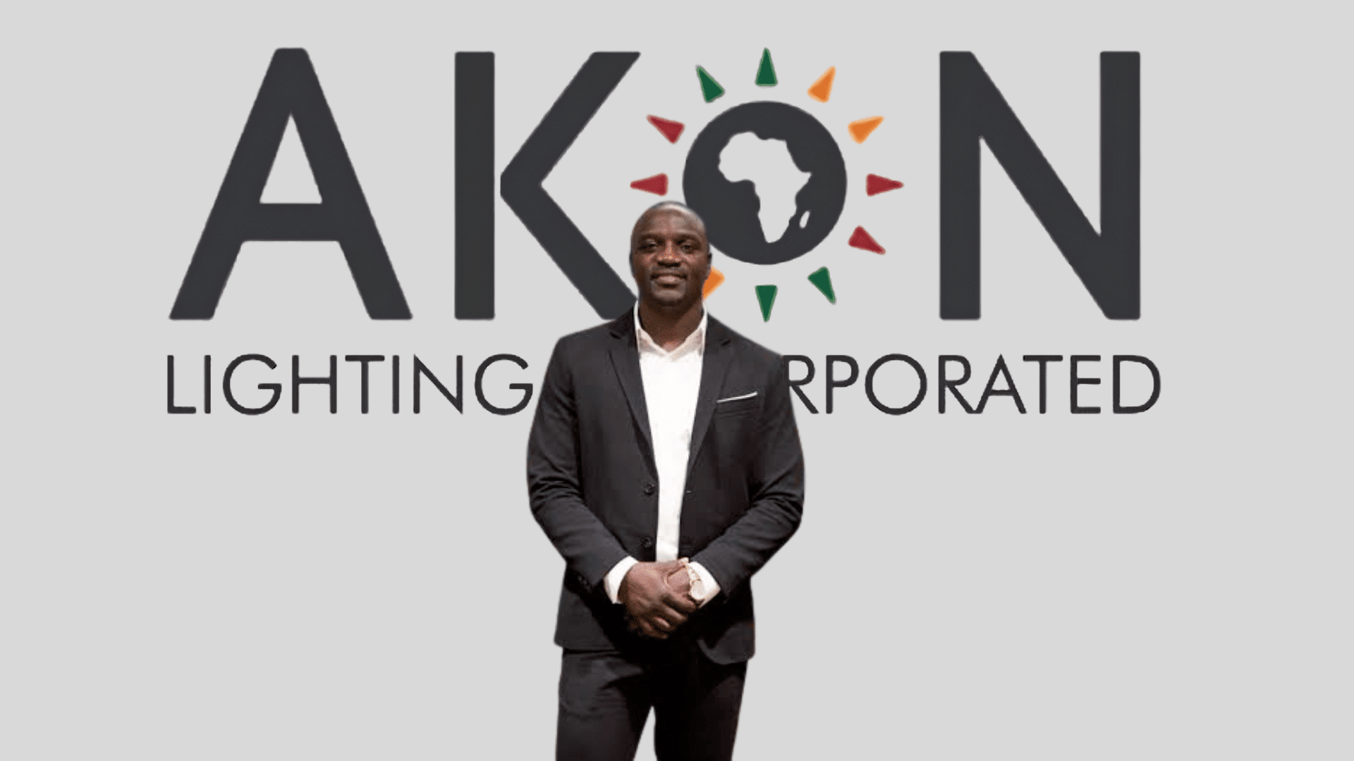 Akon standing in front of the Akon Lighting Africa corporate logo during a business presentation.