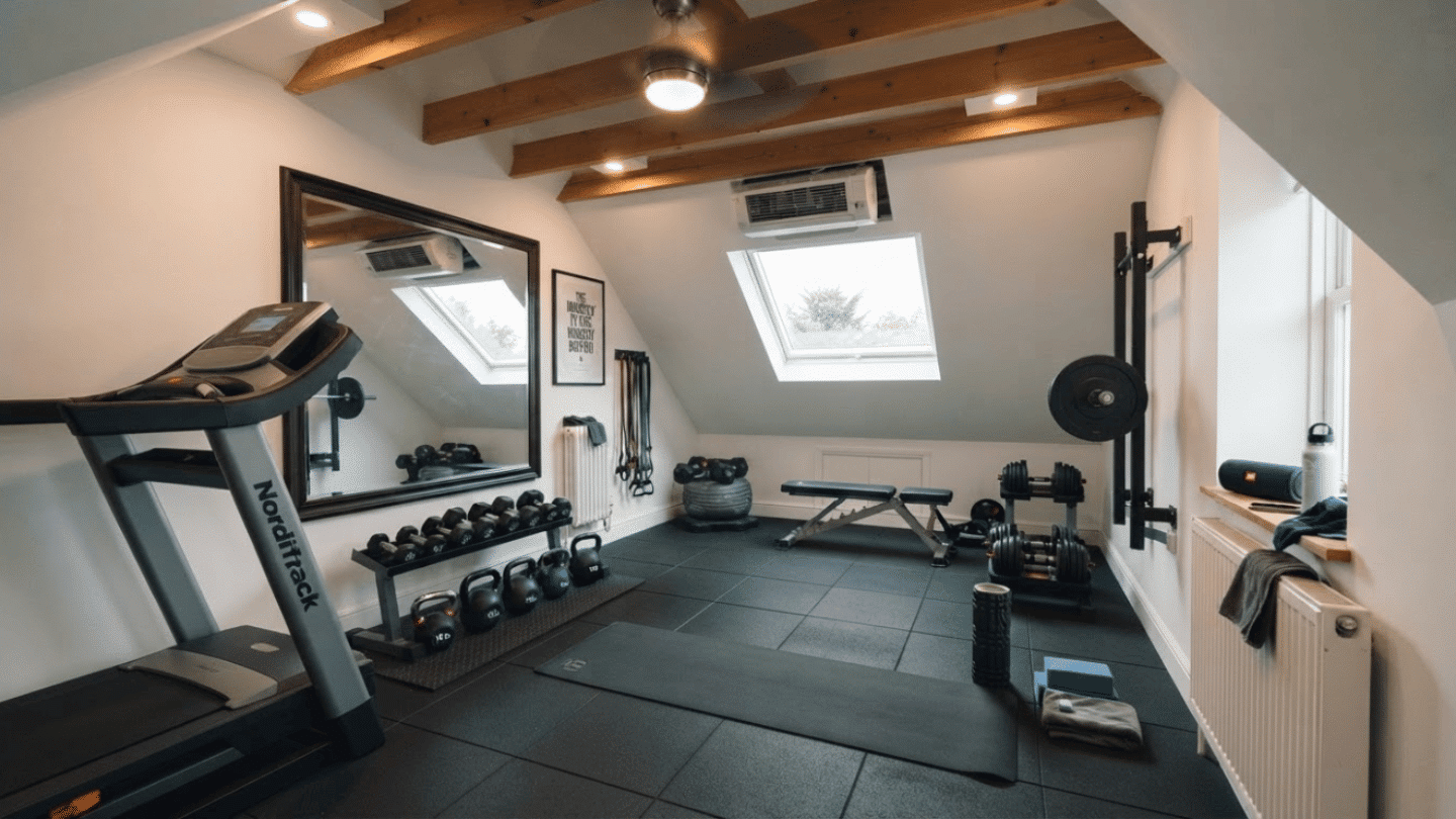 Attic gym room with fitness equipment, mirrors, flooring, and organized workout space.