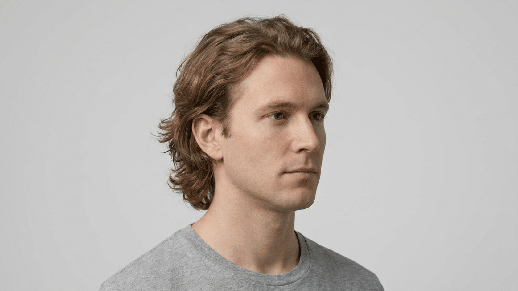 Bro flow hairstyle for men with thinning hair showing medium-length hair with natural bend and loose movement, no hard styling, three-quarter view.