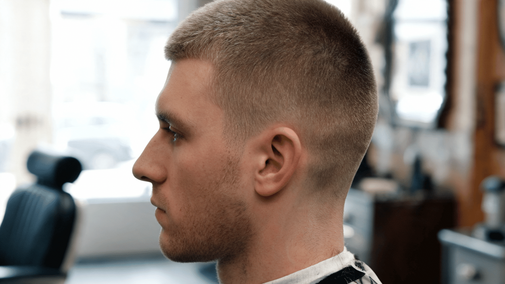 Man with a short butch cut and neatly tapered sides in a barbershop.