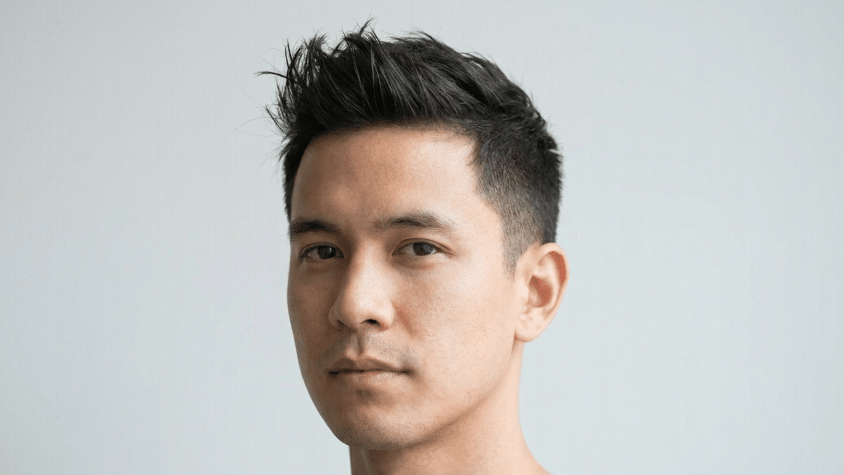 Classic quiff hairstyle for men with thinning hair showing individual strands lifted upward into a textured peak with tapered sides, front-facing view.