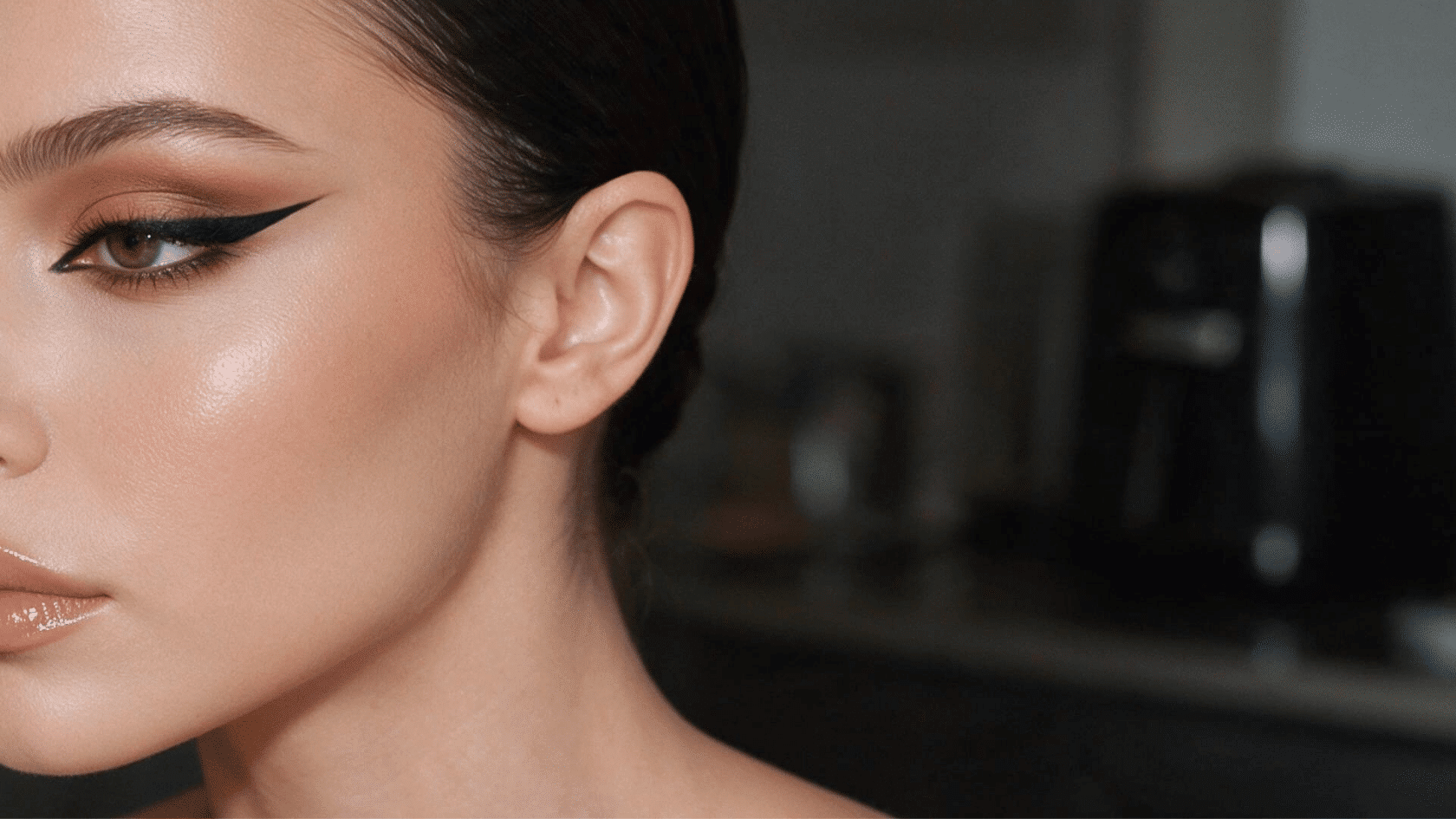 Close-up portrait highlighting almond shaped eyes with winged eyeliner and soft makeup.